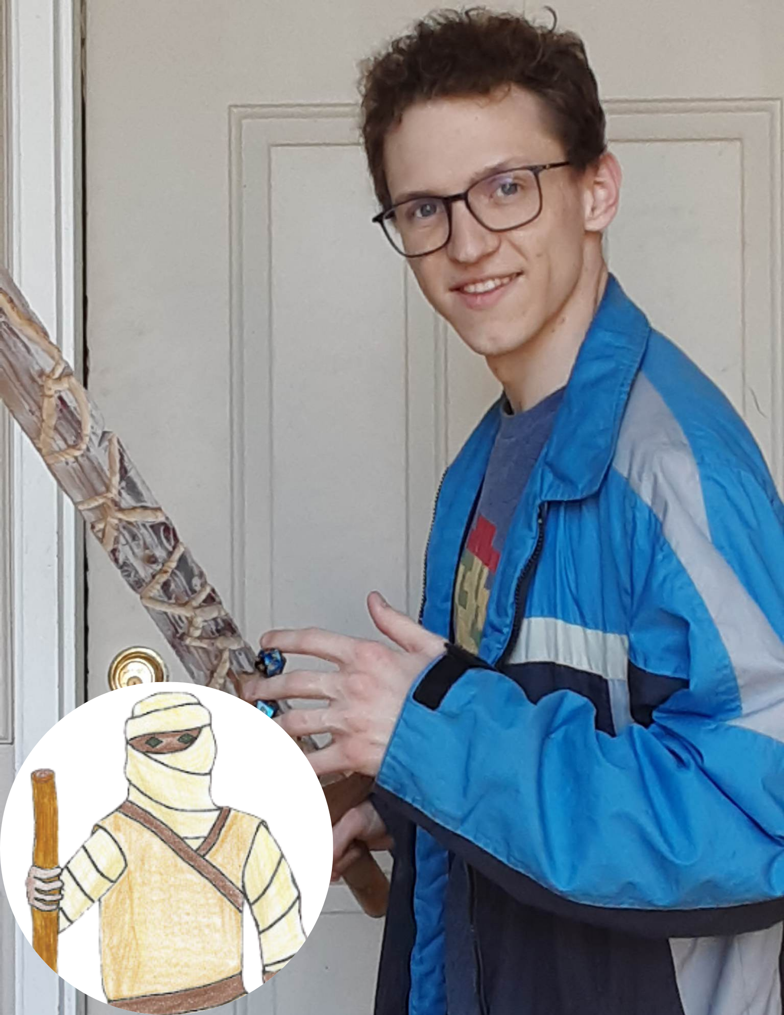 A young man with glasses, curly hair, wearing a blue and gray jacket and gray t-shirt, standing indoors in front of a door, smiling at the camera, with a large object resembling a sword or staff.