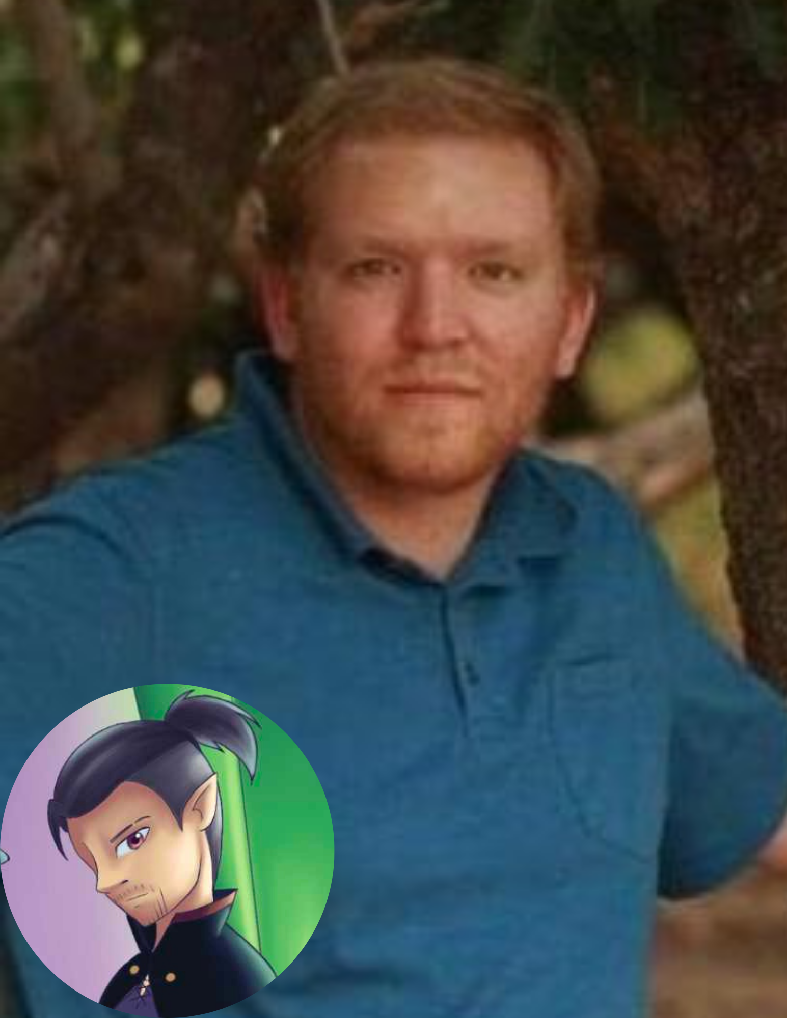 A young man with reddish hair and light beard sitting outdoors near trees, wearing a blue collared shirt.