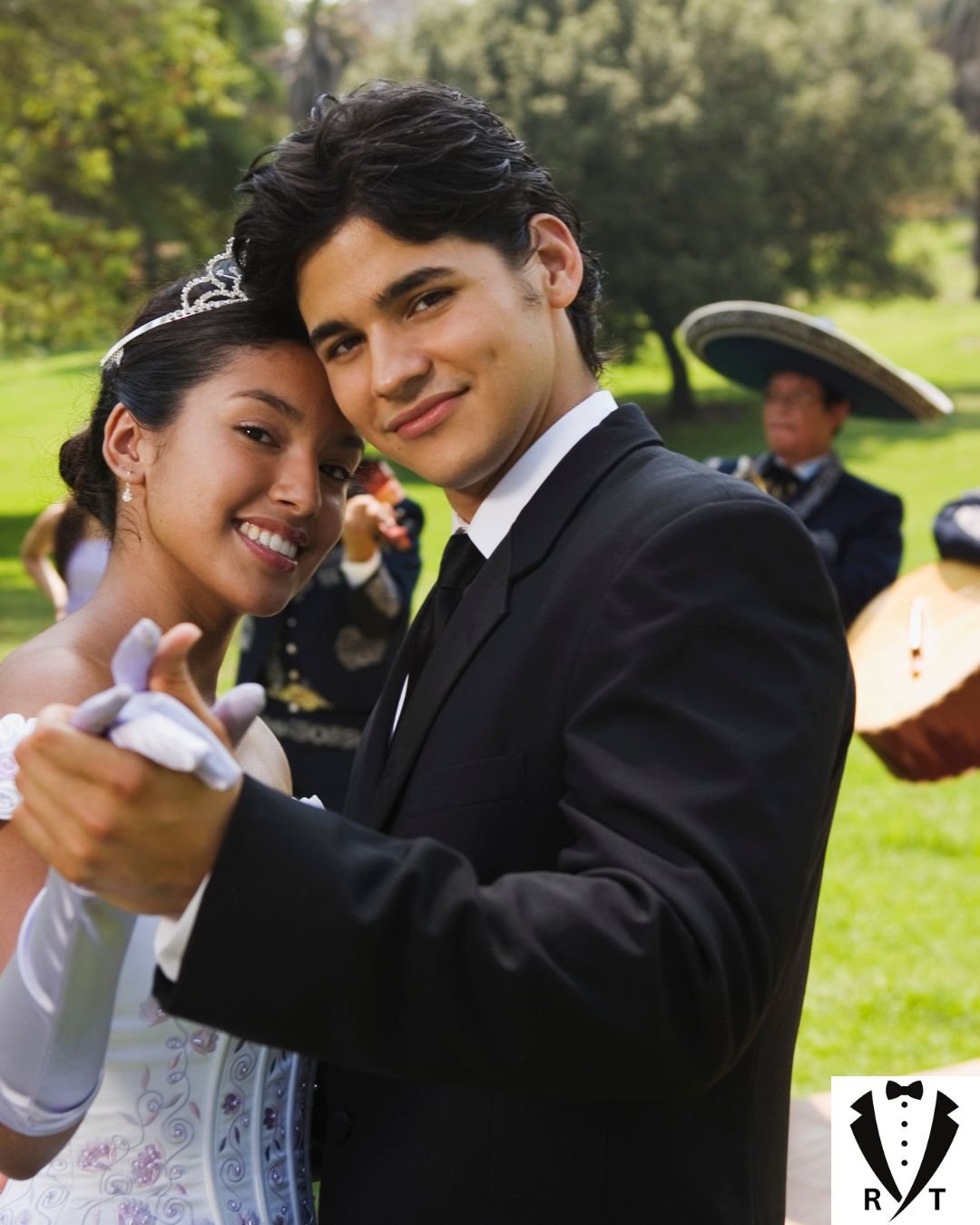 Quinceanera wearing a white dress and tiara dancing with her chambelan in a black tuxedo