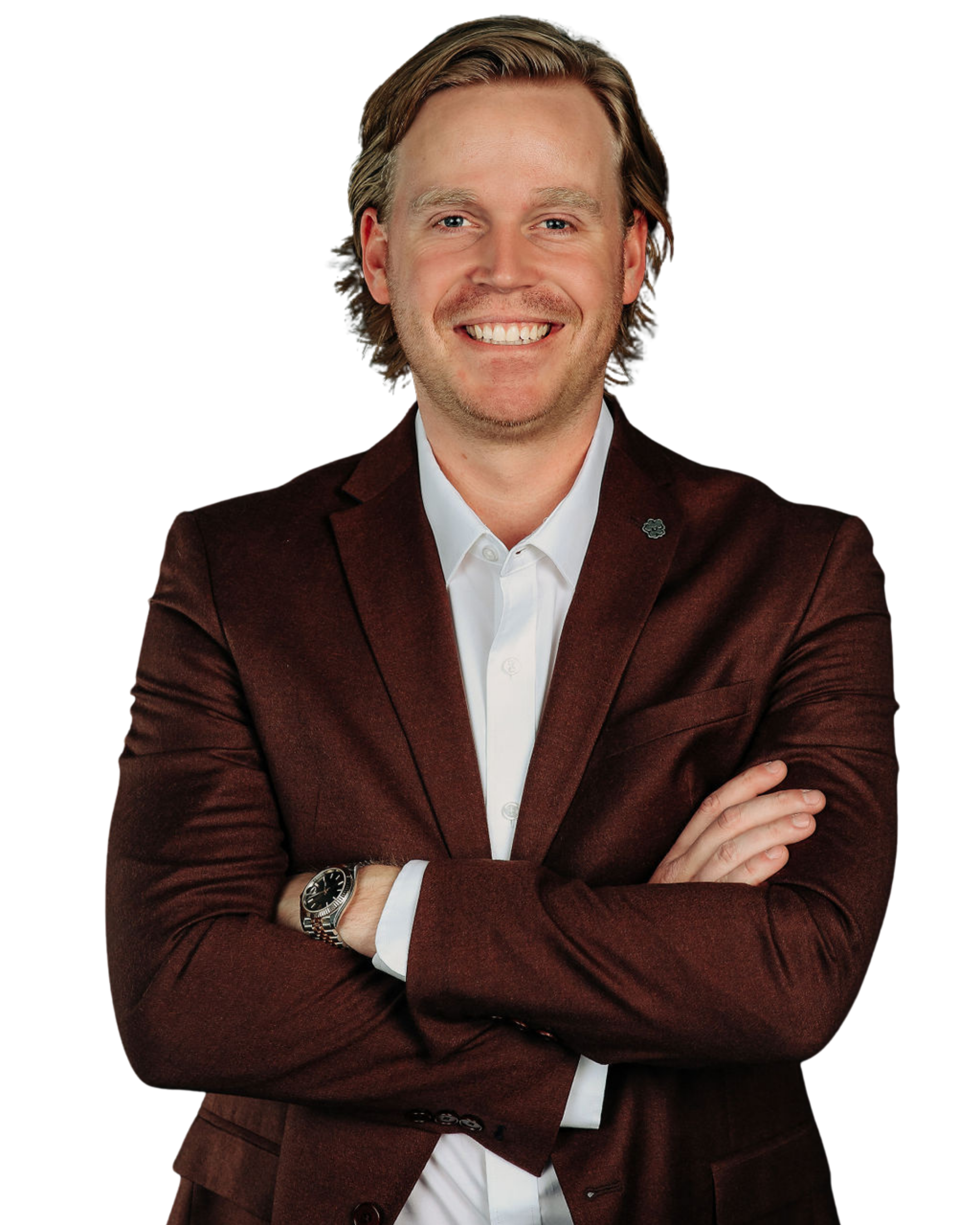 Portrait of a smiling man with light hair, wearing a white shirt, maroon blazer, and a watch, crossing his arms.