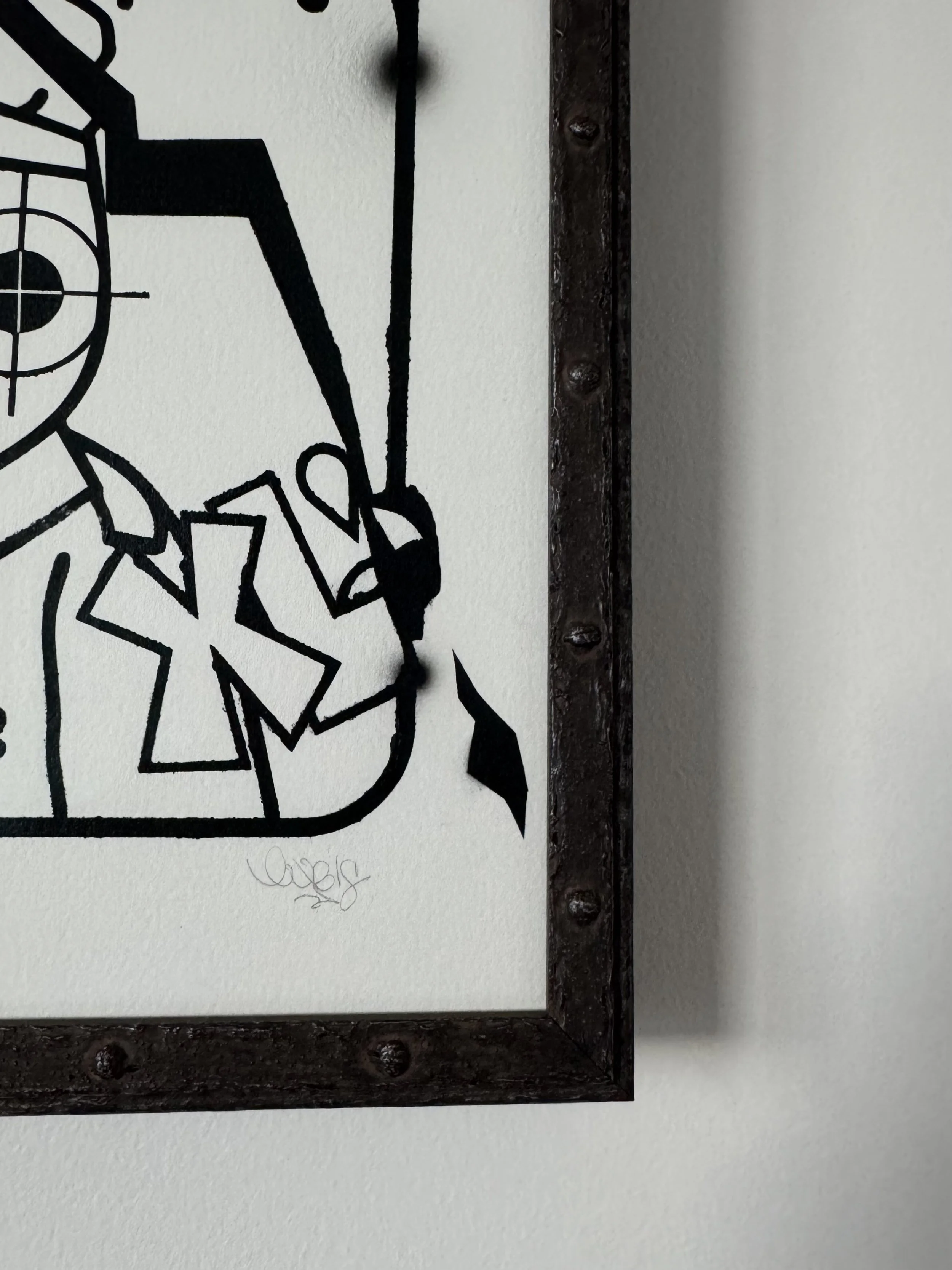 Part of a black metal wall clock with a unique design, showing the outer edge and some attachment screws, mounted on a white wall.