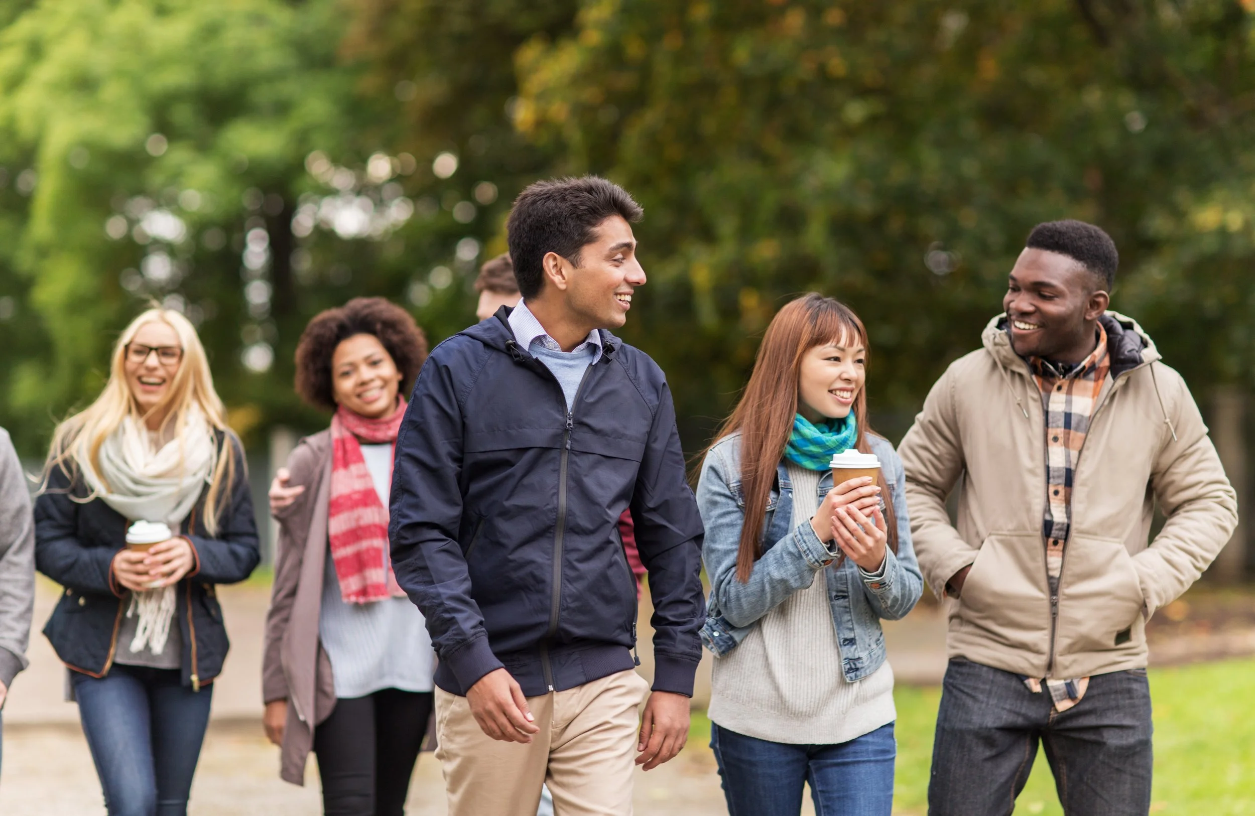 Group of friends walking together outdoors and connecting on a cool fall day.
