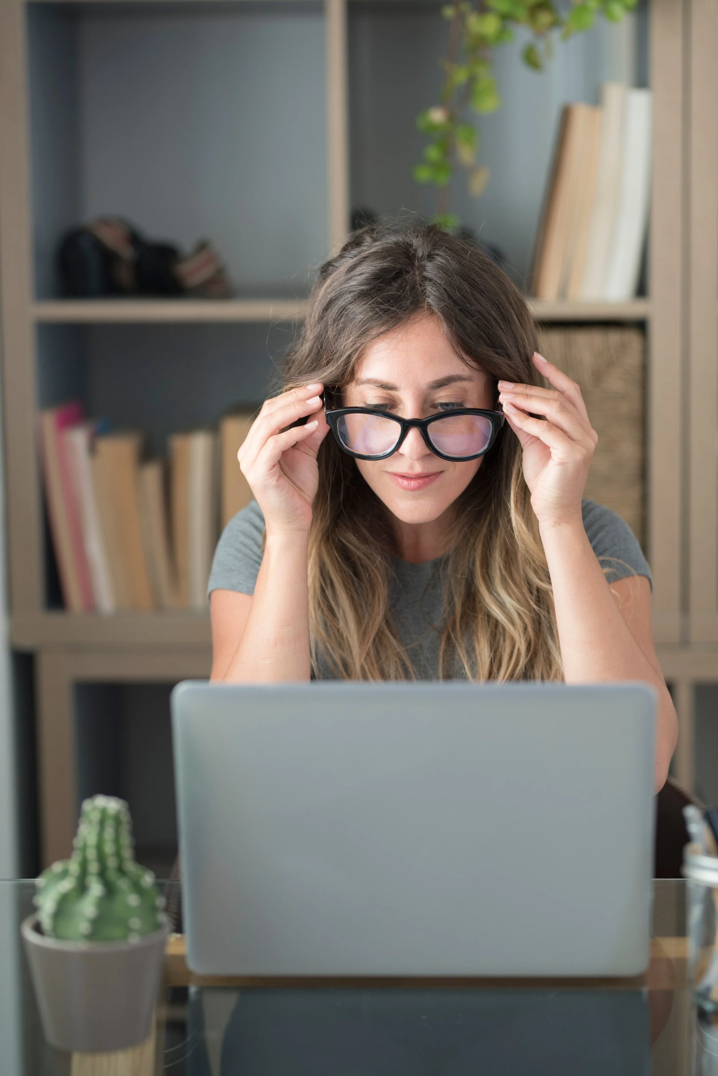 Woman at her laptop pausing during work with a tired, focused expression.