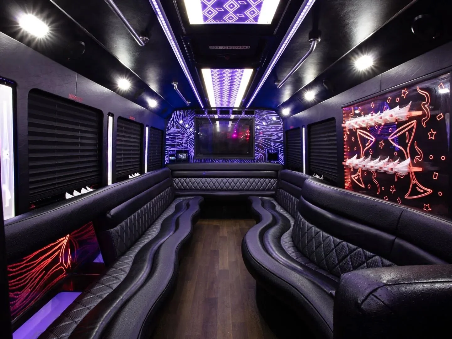 Interior of a luxury party bus with plush seating, colorful LED lights, and modern decor.
