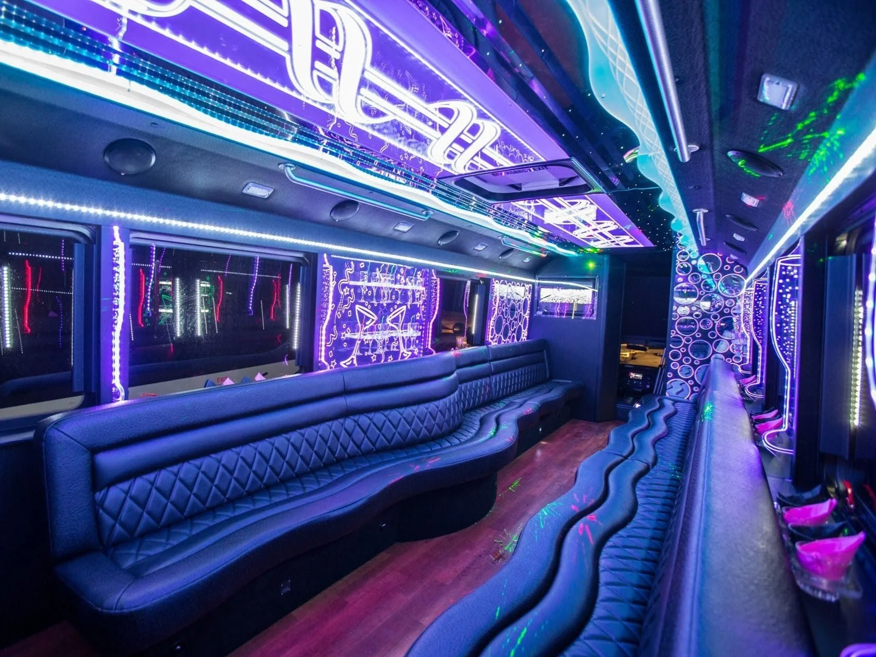 Interior of a party bus with colorful LED lights and leather seating.