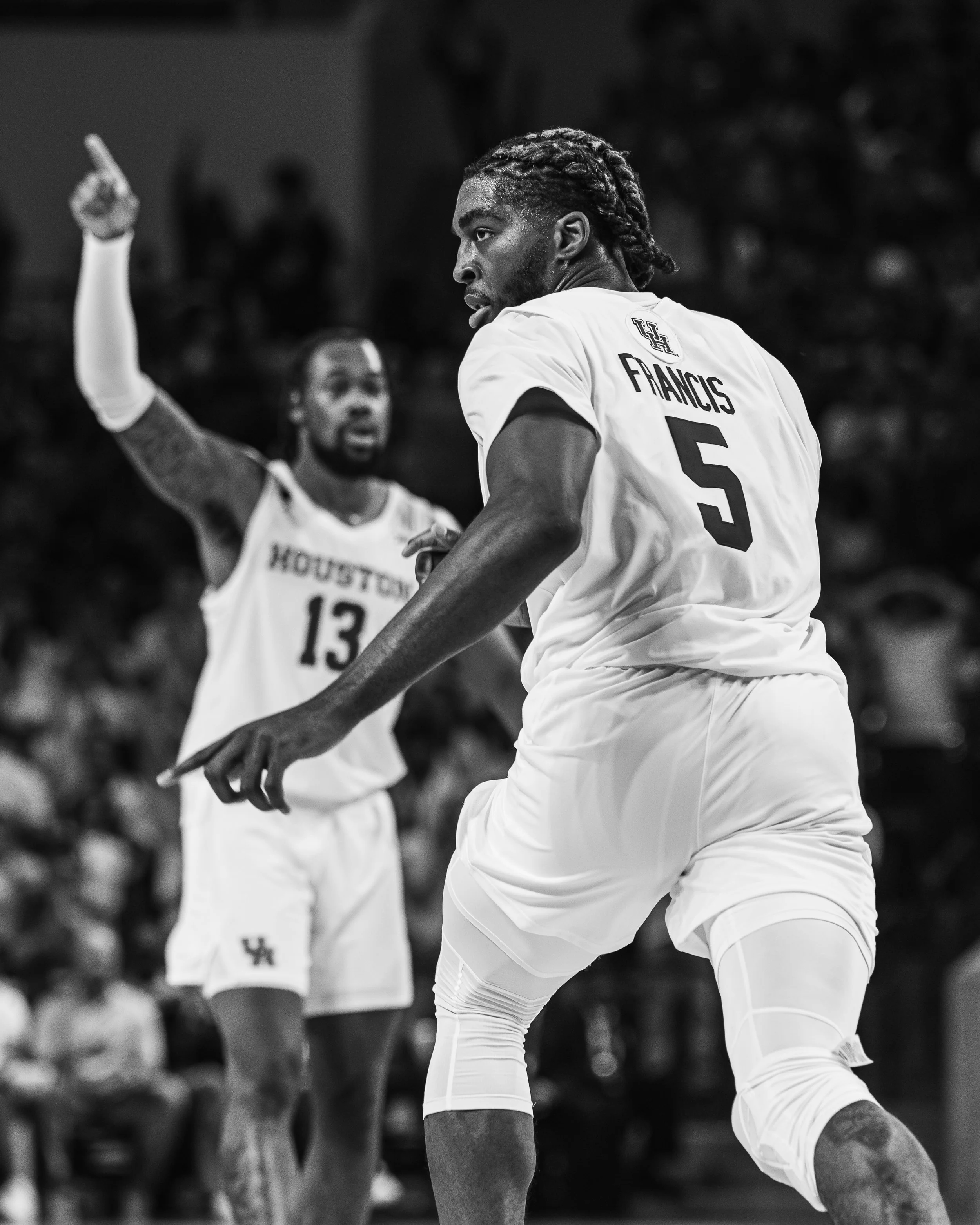 Two basketball players from the Houston team during a game, one with jersey number 5 and the other with number 13, in a black-and-white action shot.
