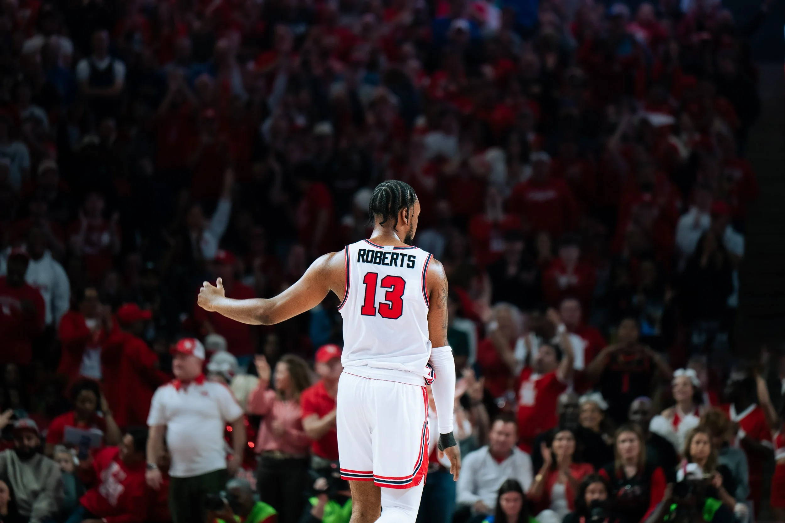 A basketball player wearing a white jersey with the name Roberts and number 13, standing on the court with a crowd of spectators in the background.