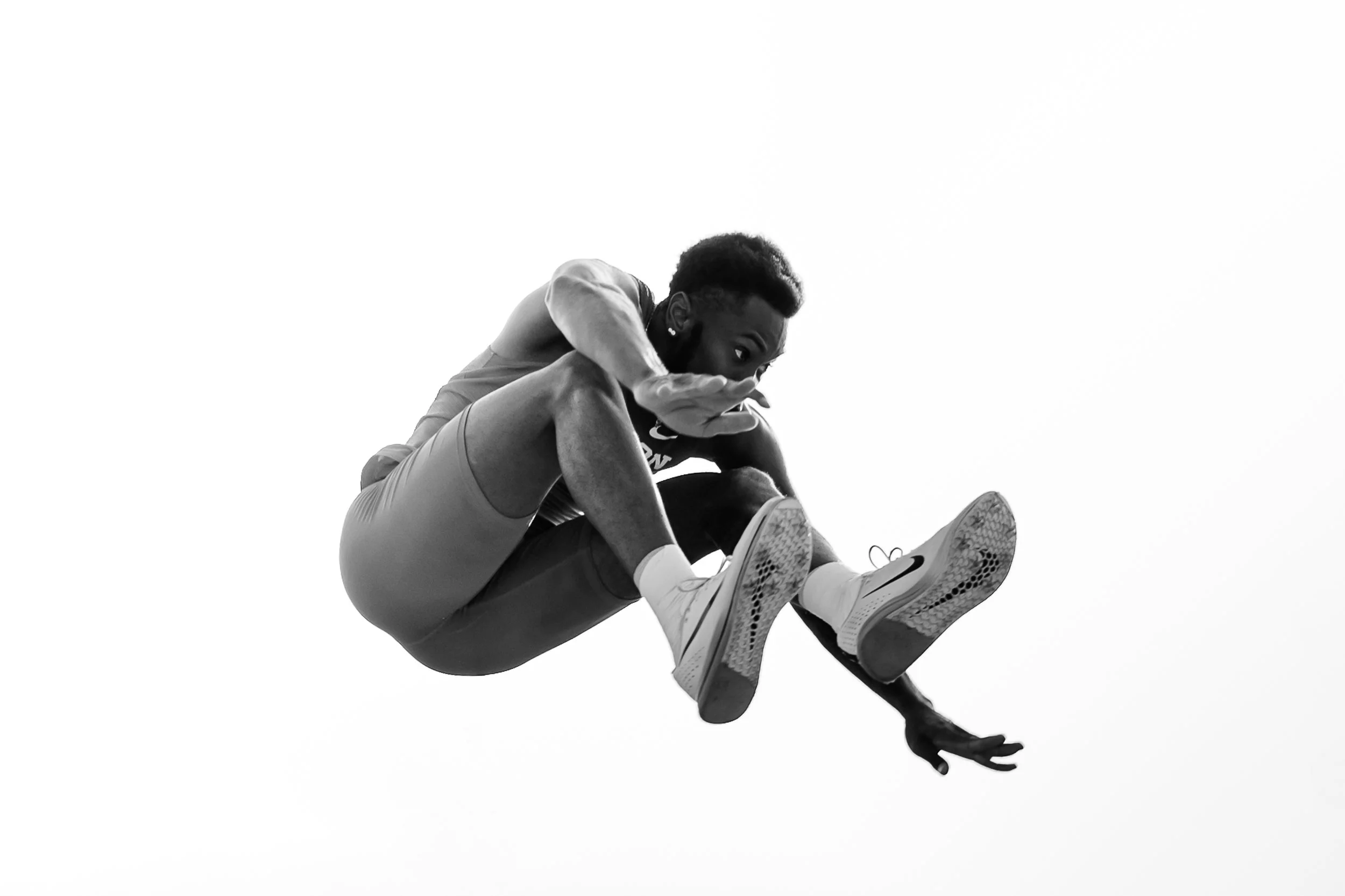 Black and white photo of a person mid-air performing a parkour move, with a plain white background.