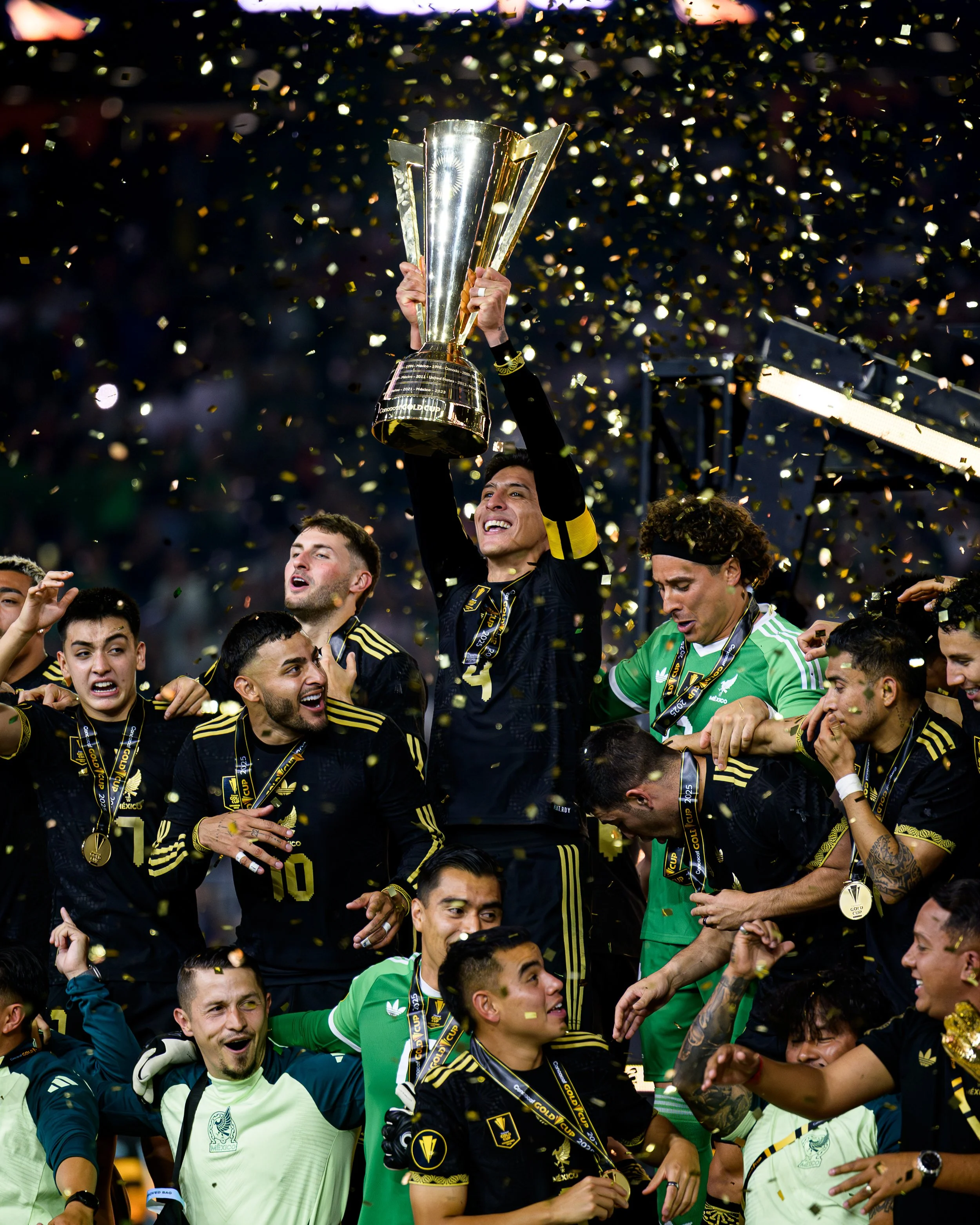 Soccer players celebrating a victory with a trophy, surrounded by falling confetti.