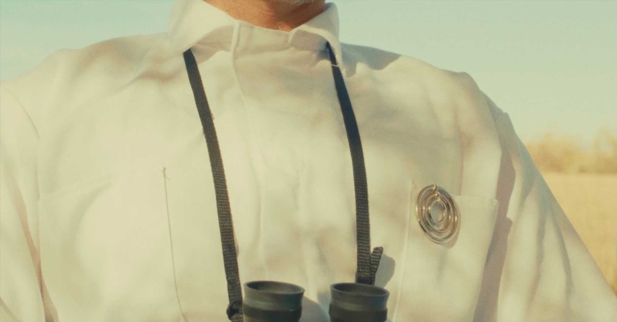 Person in white medical coat with a stethoscope hanging around neck, holding two black cups.