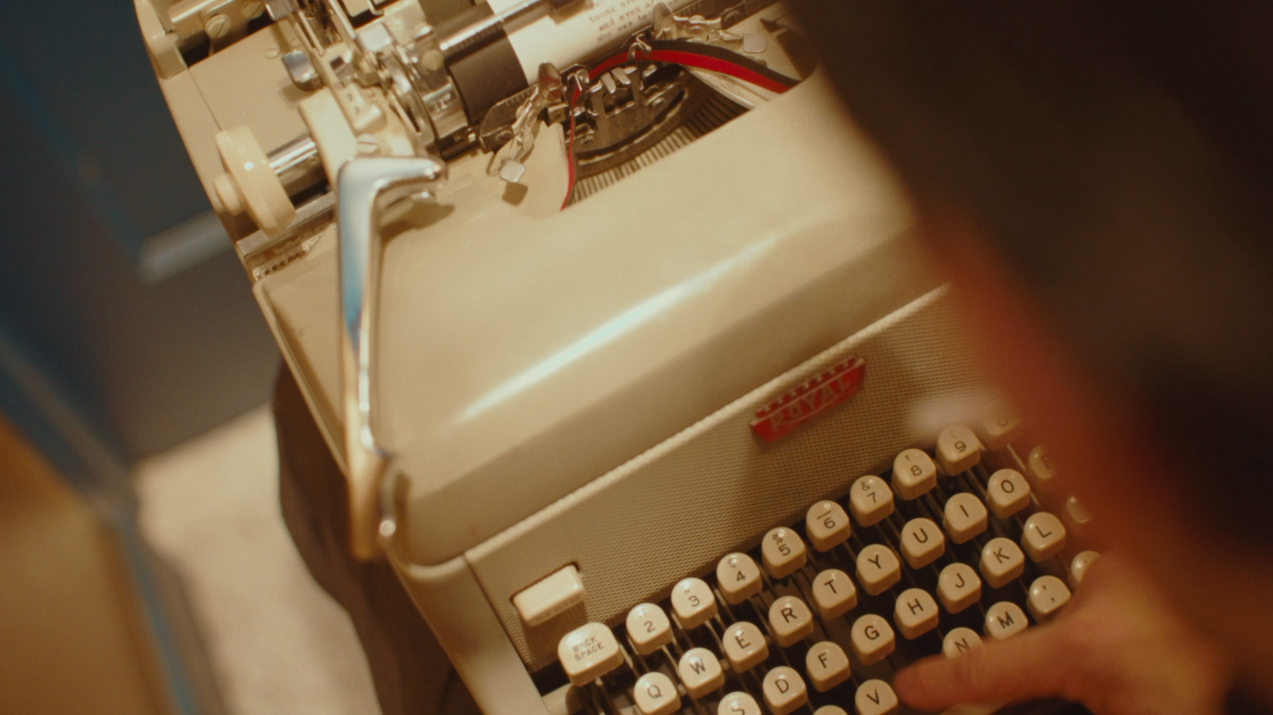 Close-up of a vintage beige typewriter with round keys, showing the internal metal mechanisms and red and black ink ribbon.