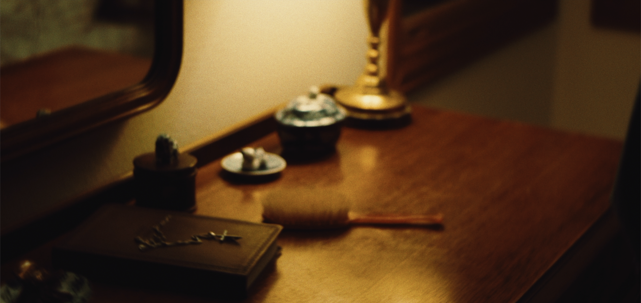 A wooden surface with various small decorative items, including small dishes, a candle, and a mirror in the background.