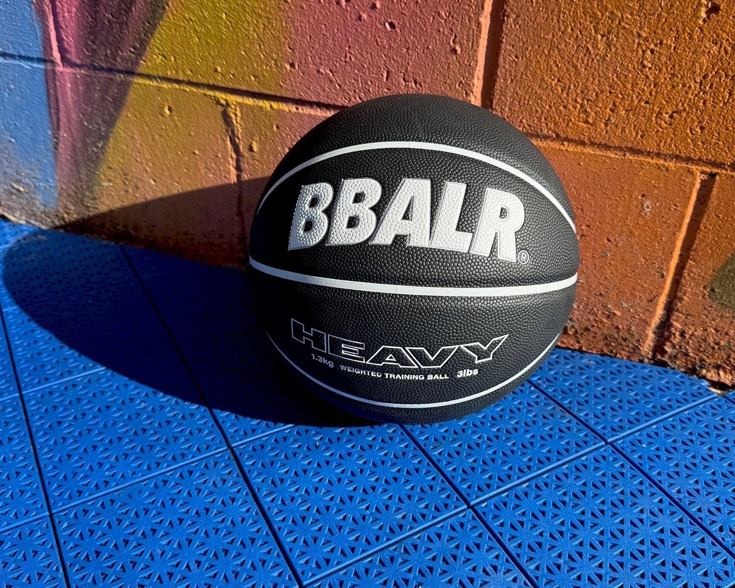 Black basketball with 'BBALR' logo on blue court against colorful wall