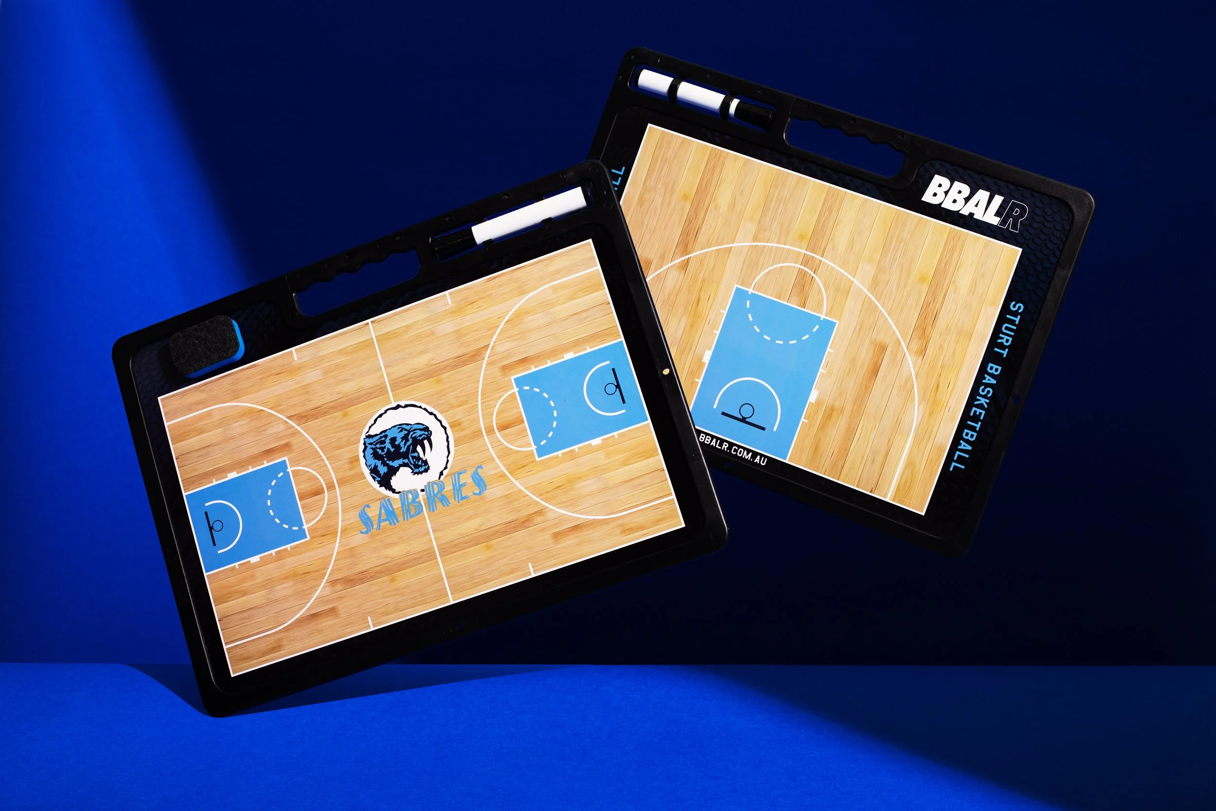 Two basketball playboards with court designs and markers on a blue background.