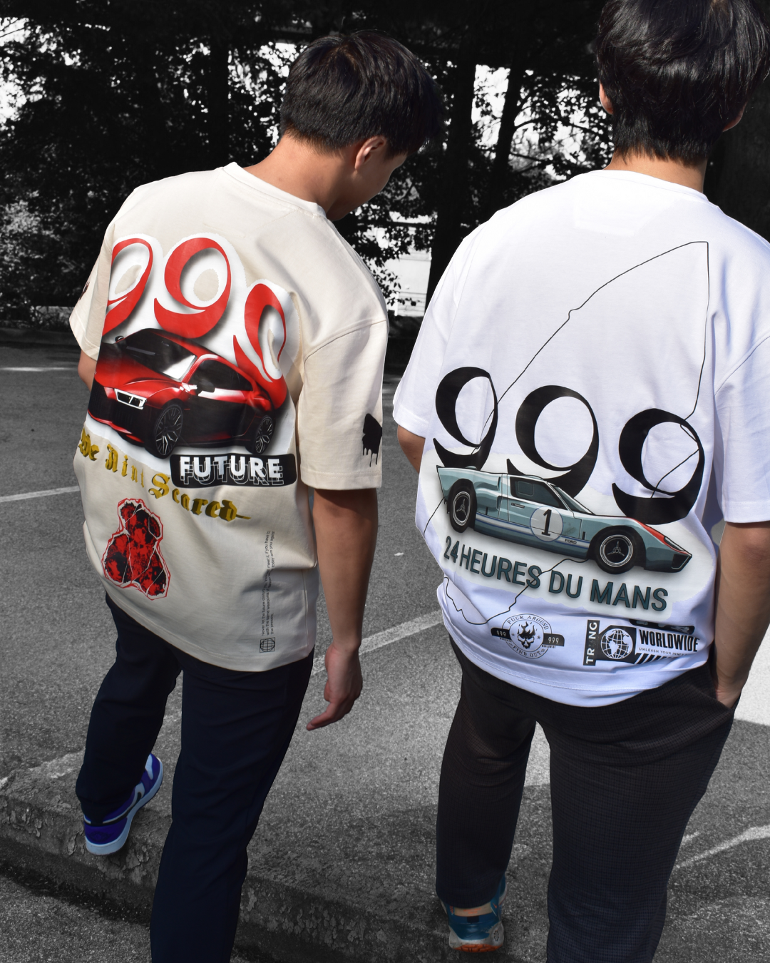 Two young men standing in a parking lot wearing graphic t-shirts with vintage car designs and racing-related text and logos.