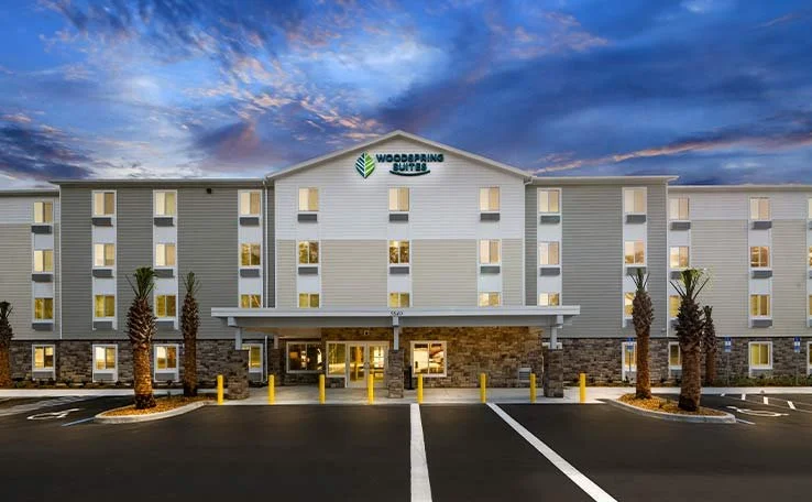 WOODSPRING-SUITES-PTORANGE-EXTENDED-STAY-HOTEL-EXTERIOR-DUSK-1-738X456.jpg