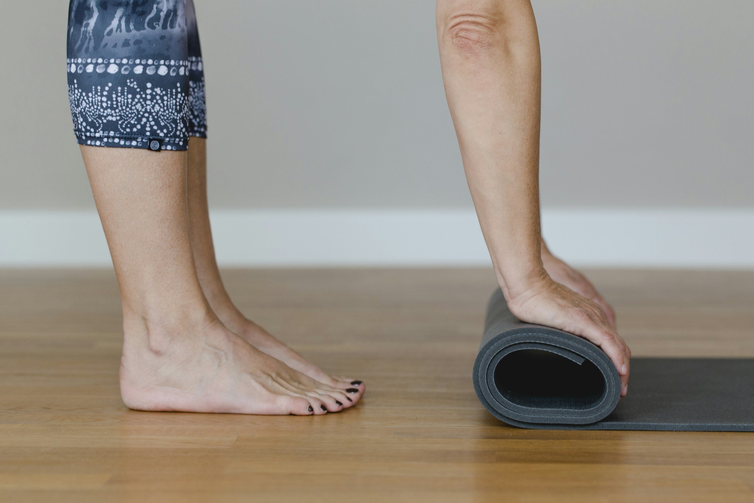 A person using a foam roller on their calf muscle in a fitness or yoga setting.