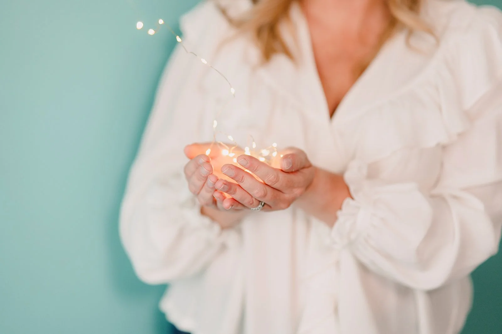 Close-up of hands holding warm fairy lights, symbolizing inner work, light, and holistic clarity.