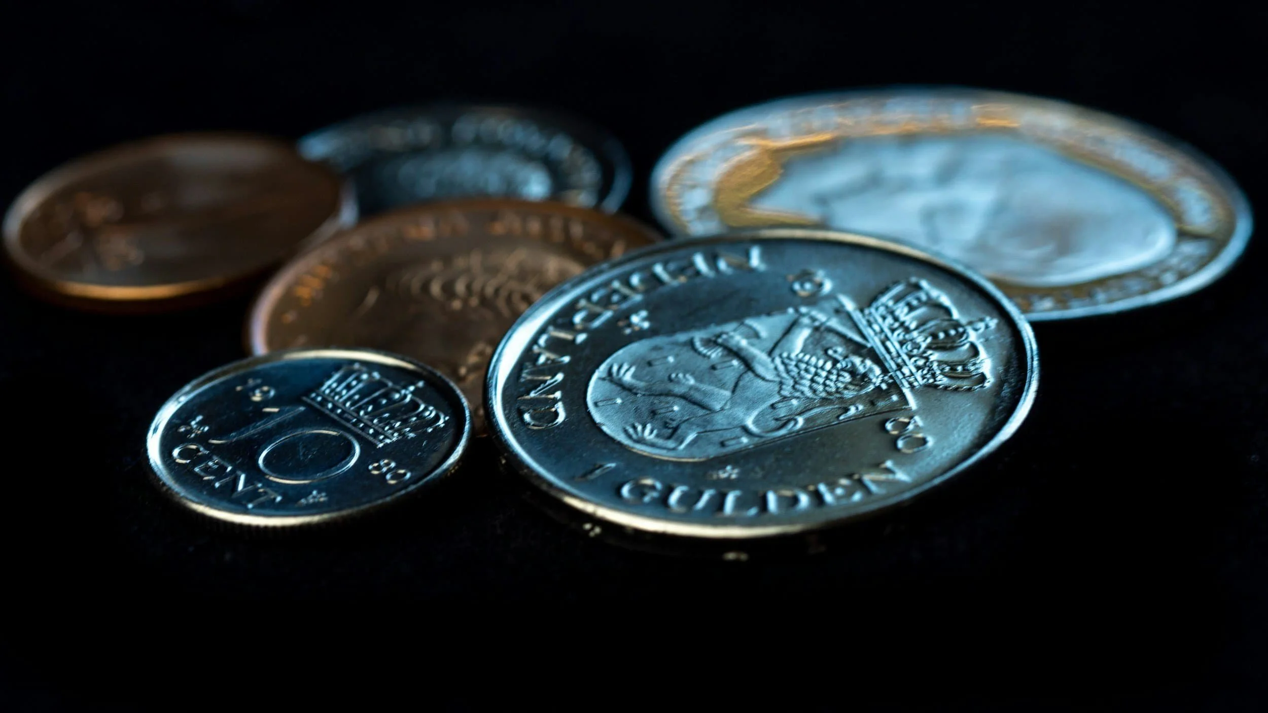 Assorted coins from different countries displayed on a dark surface, like getting paid as an architect in multiple currencies.