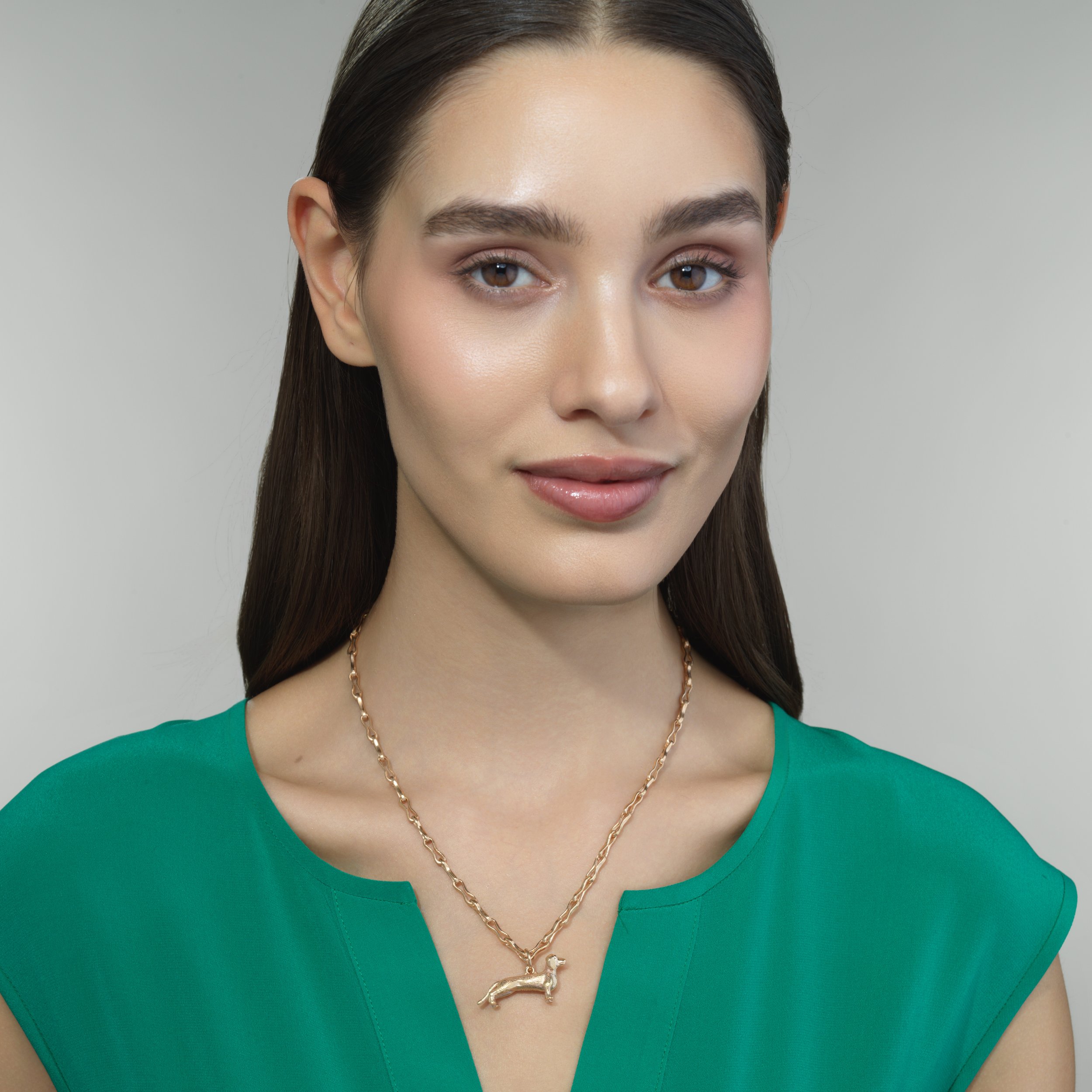 Dachshund gold pendant shown on a model for scale
