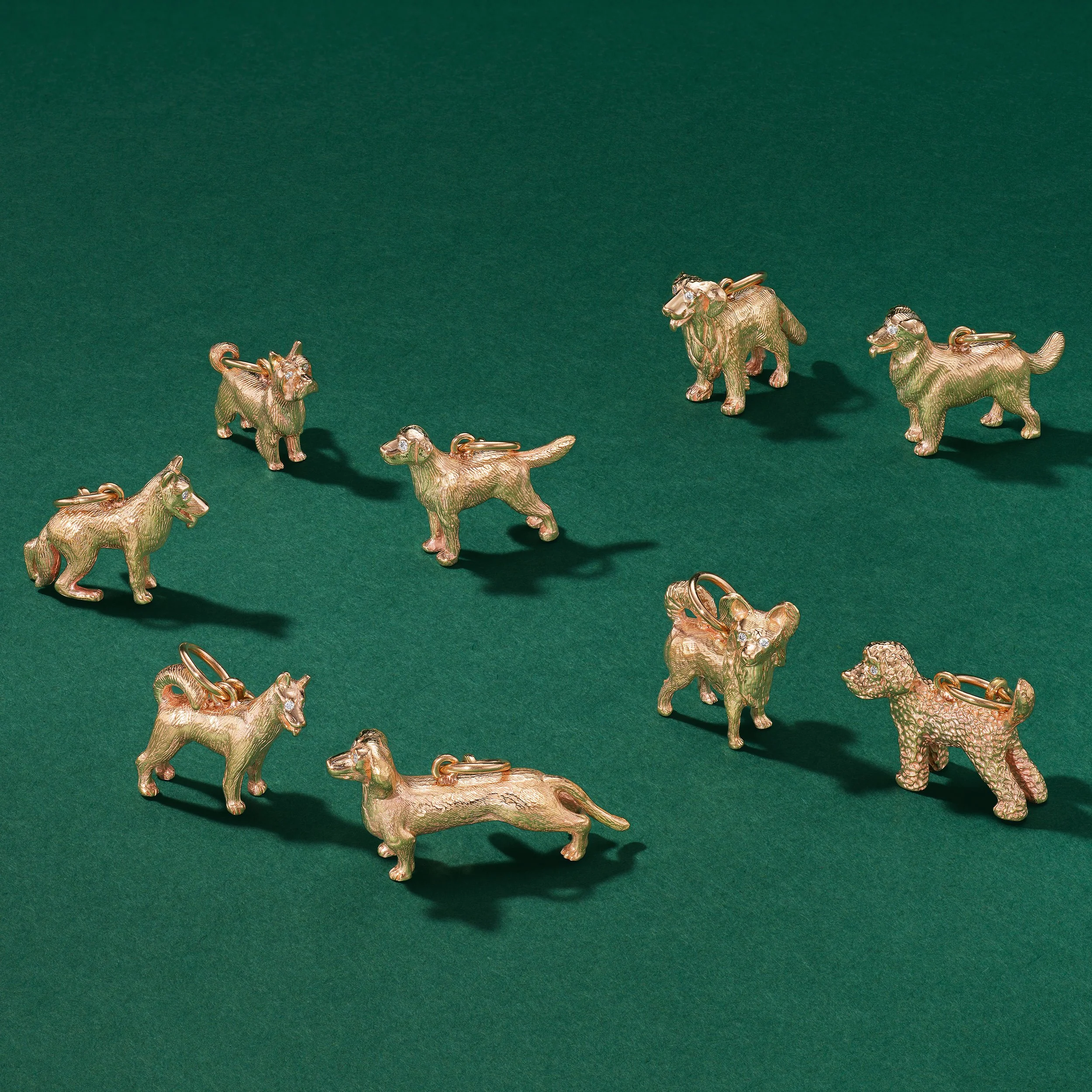 Gold animal-shaped charms on a green background, including dogs, cats, and other creatures.