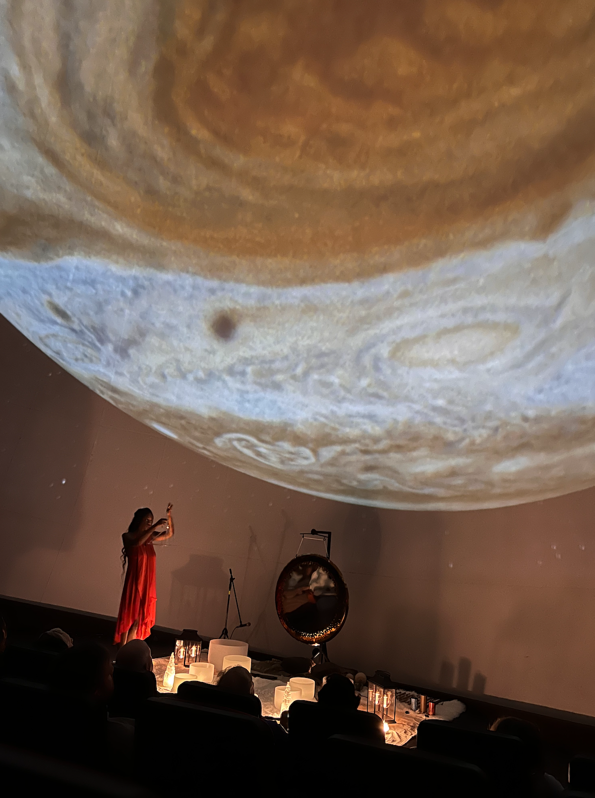 Erica Nagel of 11 11 Sound Healings performing an immersive sound healing, sound bath meditation, at Calusa Nature Center & Planetarium, featuring a cosmic planet projection over a seated audience.