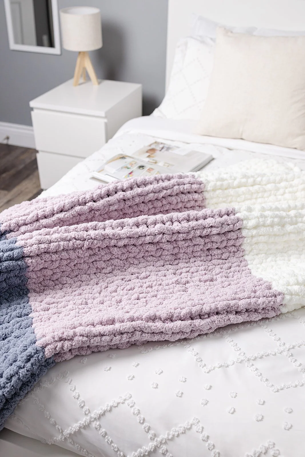 The Dini chunky knit blanket styled on a bed