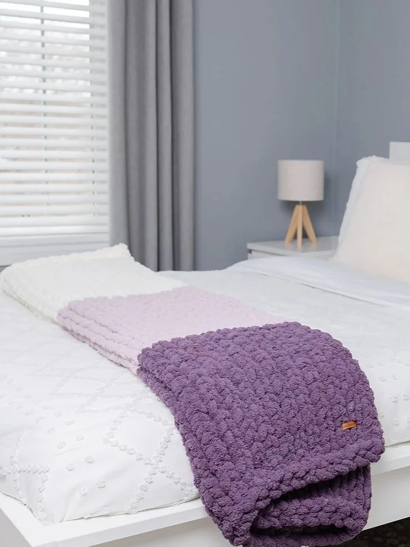Cozy violet chunky knit throw folded in a neutral living room