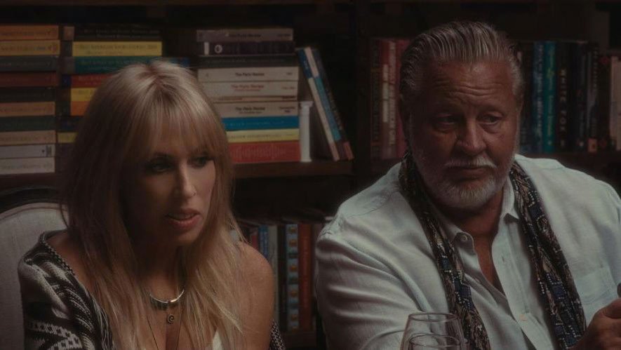 Two people sitting at a table with bookshelves in the background.