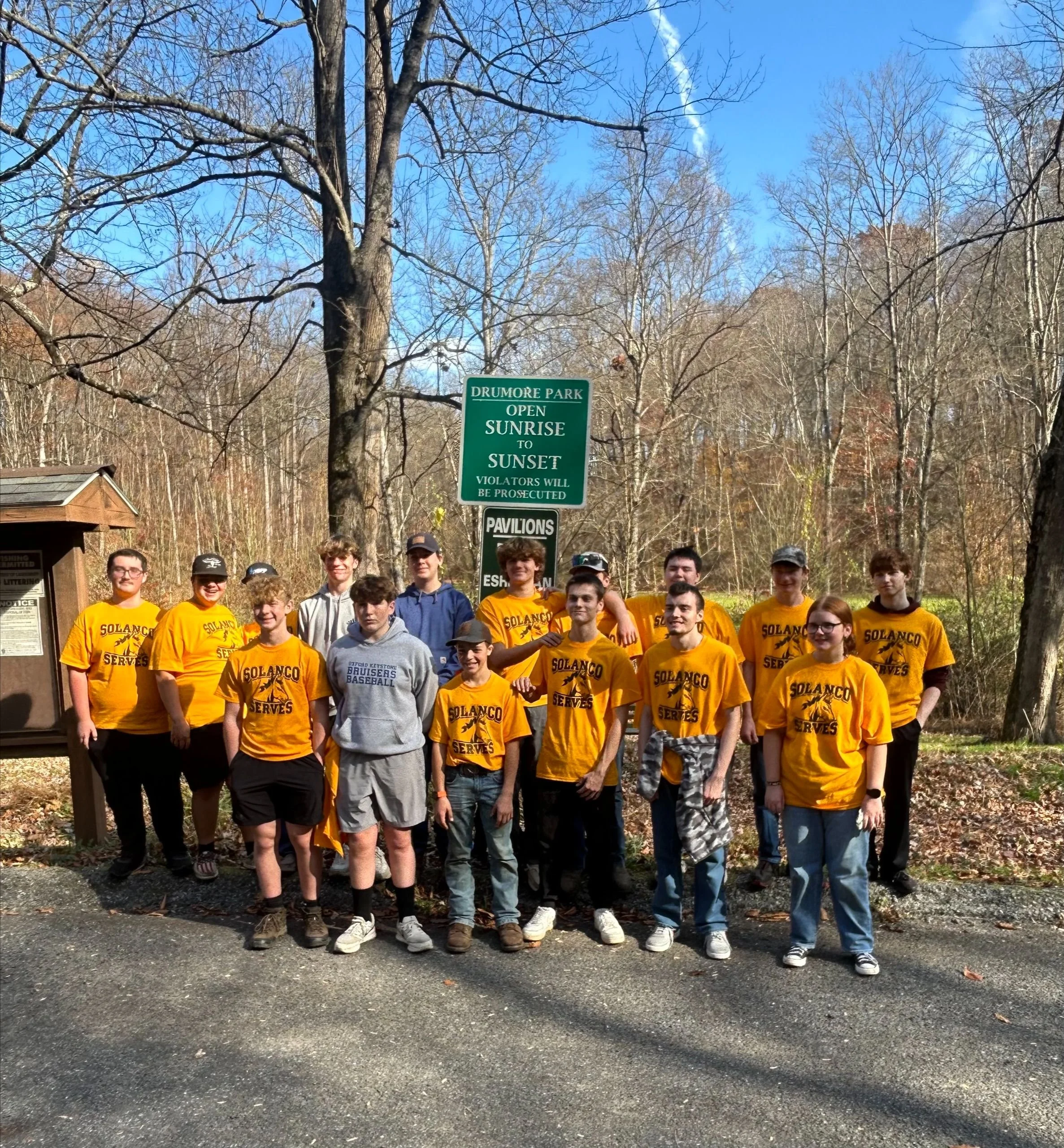 Group of pre teens in matching yellow shirts smiling at camera