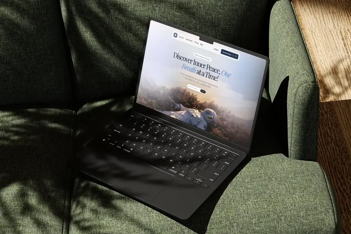 A black laptop on a green cushioned chair, displaying a website designed by Saf Designs Studio with the text "Discover Inner Peace, One Breath at a Time!" and an image of a person lying on the ground outdoors with a scenic background.