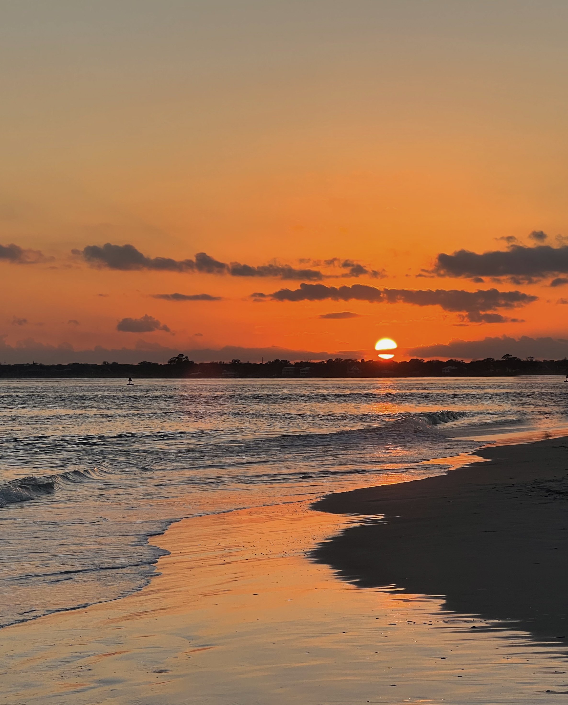 Sunset over the ocean with reflections on the water and dark clouds on the horizon.