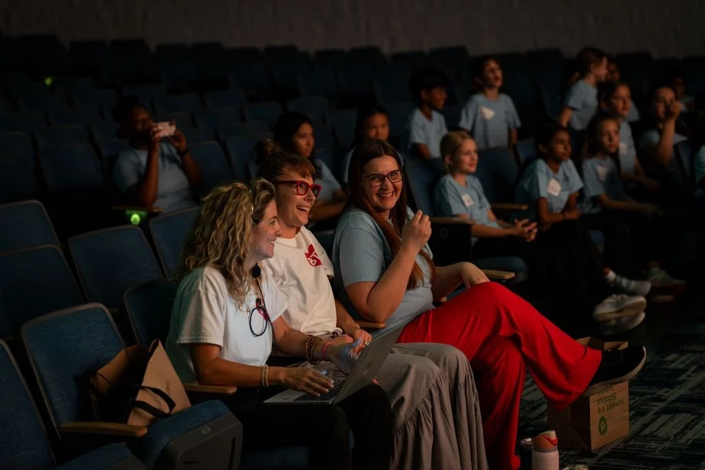 Three women smiling in a theater