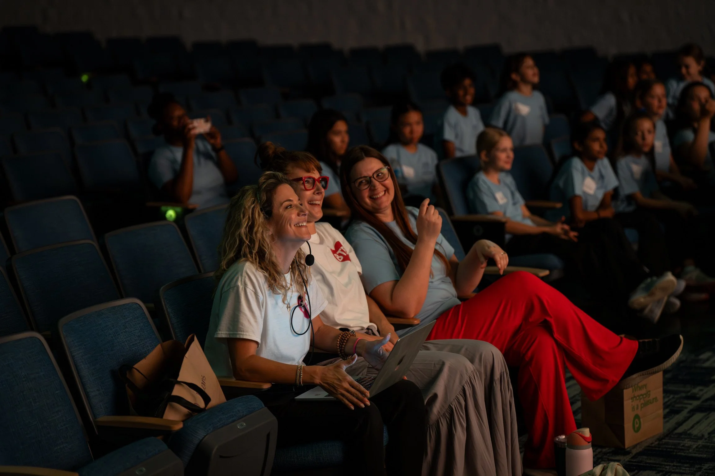Three women smiling in a theater
