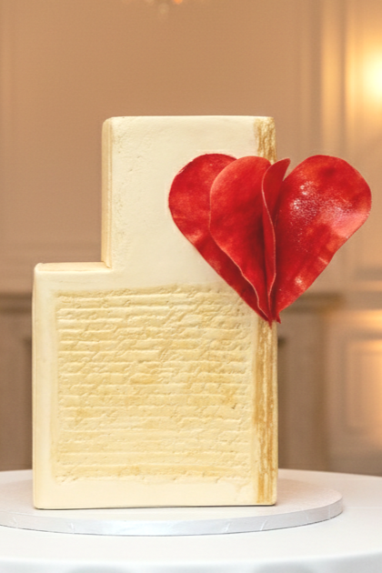 Minimalist two-tiered cake with a huge 3D red edible heart design, presented on a white pedestal stand—elegant custom cakes in Calgary by Magnolia Couture Cakery.