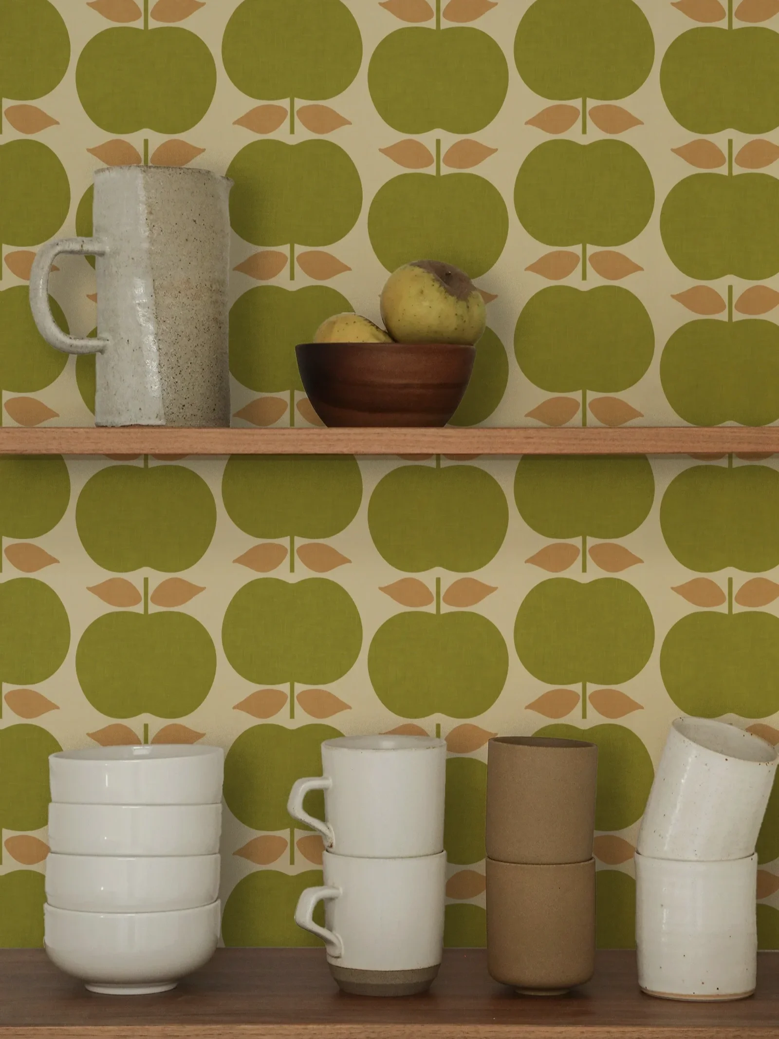 retro kitchen green apple wallpaper behind shelves with cups, bowls and pears
