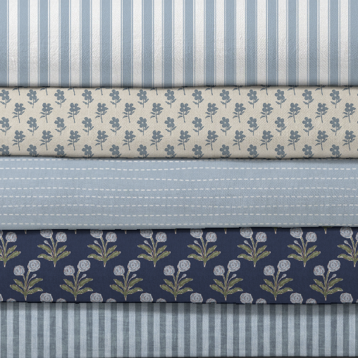 stack of fabric rolls with varying floral and stripe designs in shades of blue