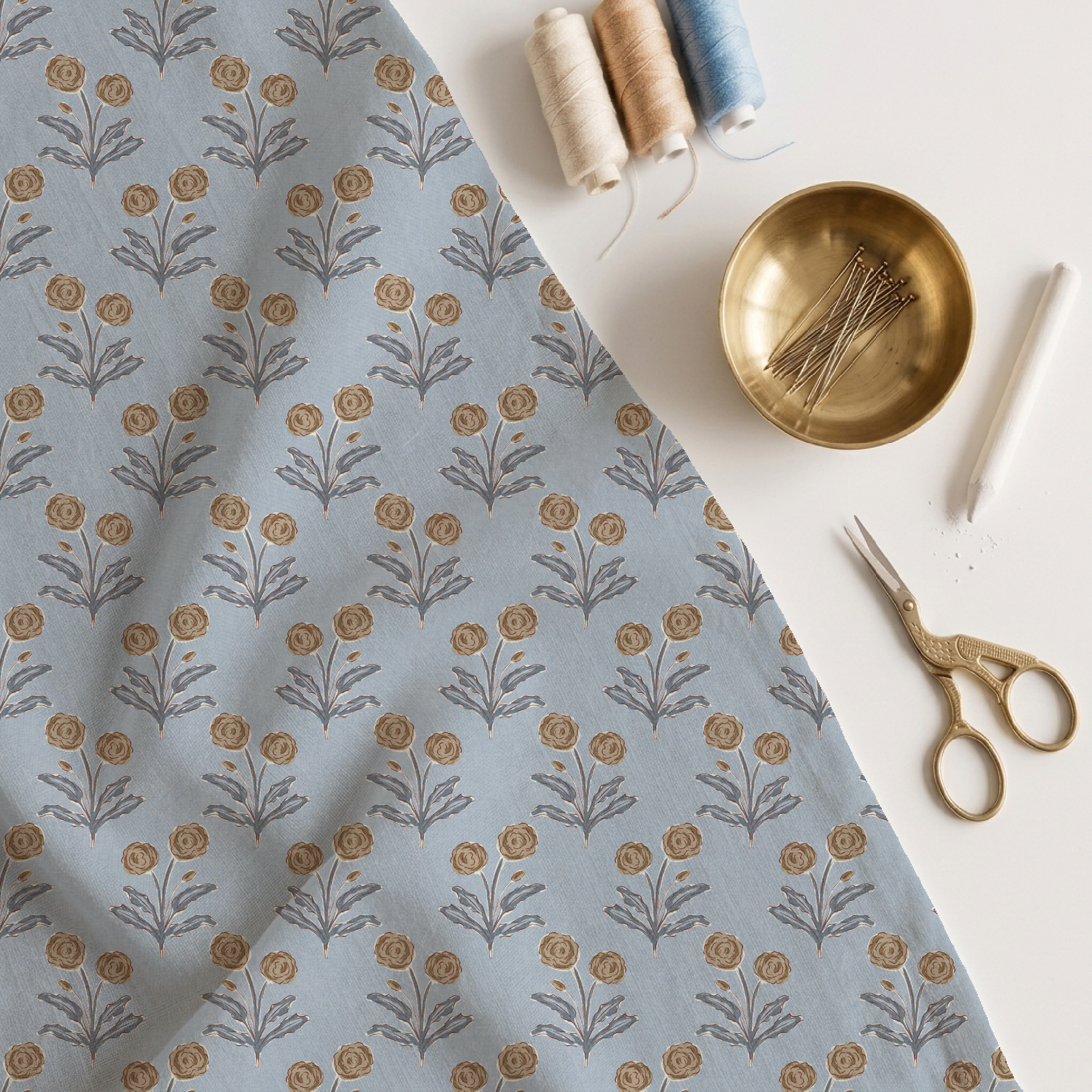 fabric with a marigold block print pattern, scissors, pins and reels of thread