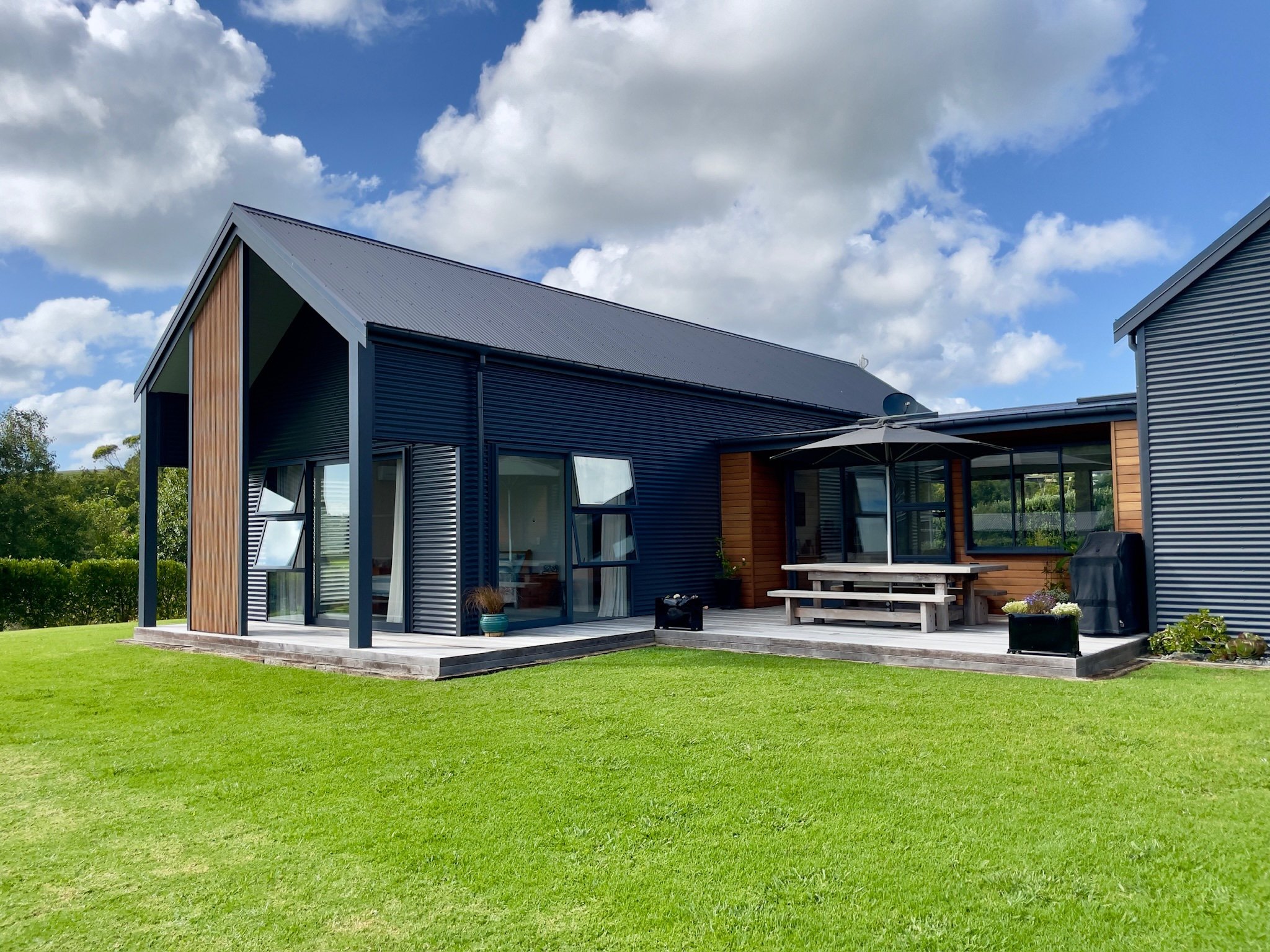 Contemporary new home build with dark cladding and landscaped lawn, Elite Building Northland