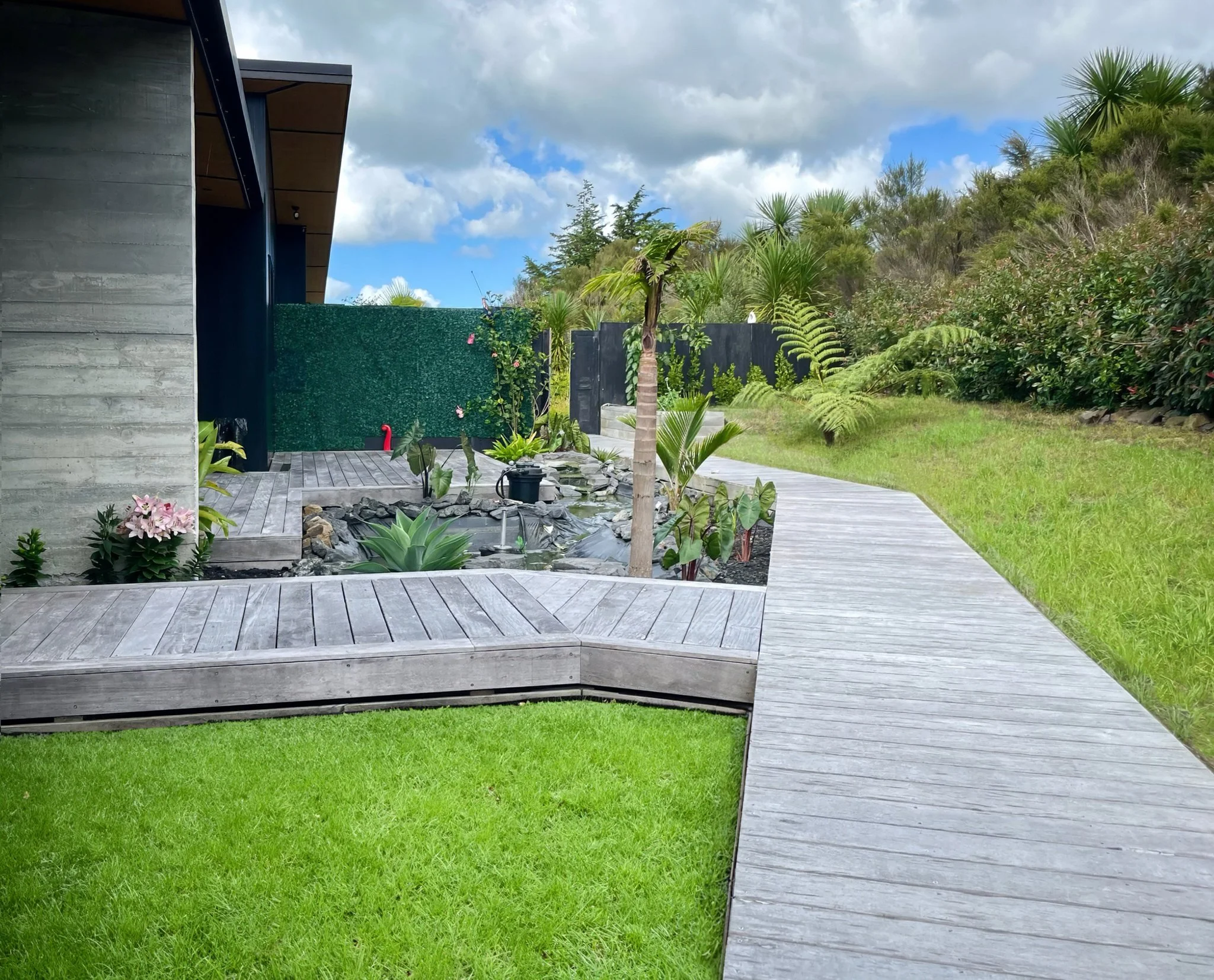 Sanctuary Ridgeview new home side elevation with timber decking and Koi Pond Mangawhai