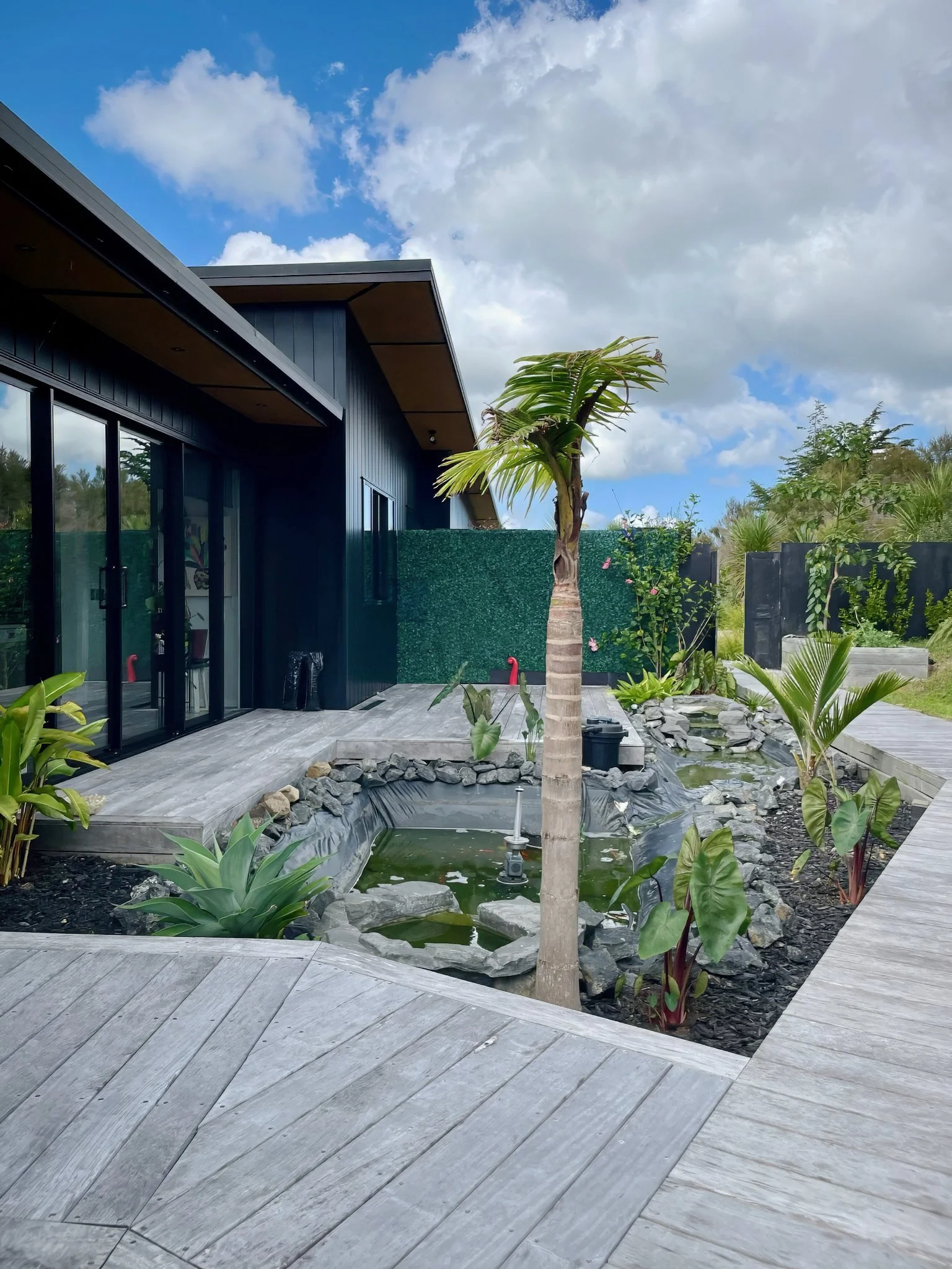 Sanctuary Ridgeview new home side elevation with dark cladding and timber decking, Northland