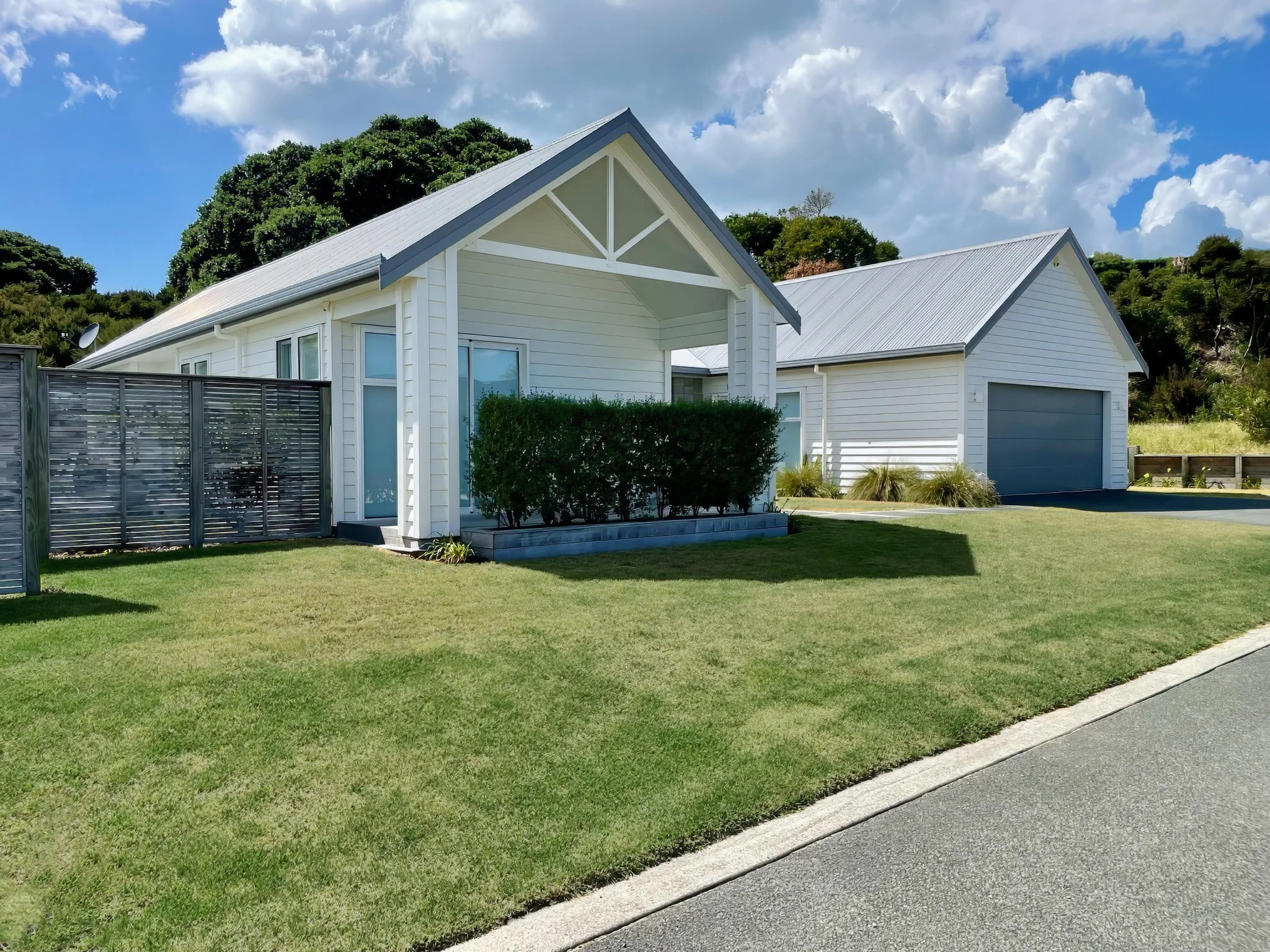 New home build with traditional white exterior and manicured gardens, certified builders Mangawhai