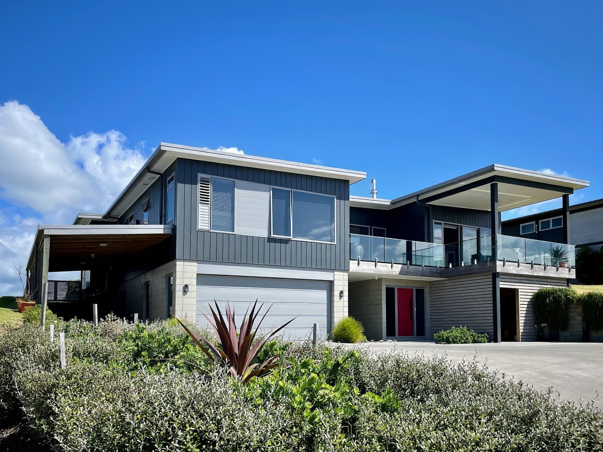 Driftwood family new home build front elevation with dark cladding and double garage, Mangawhai