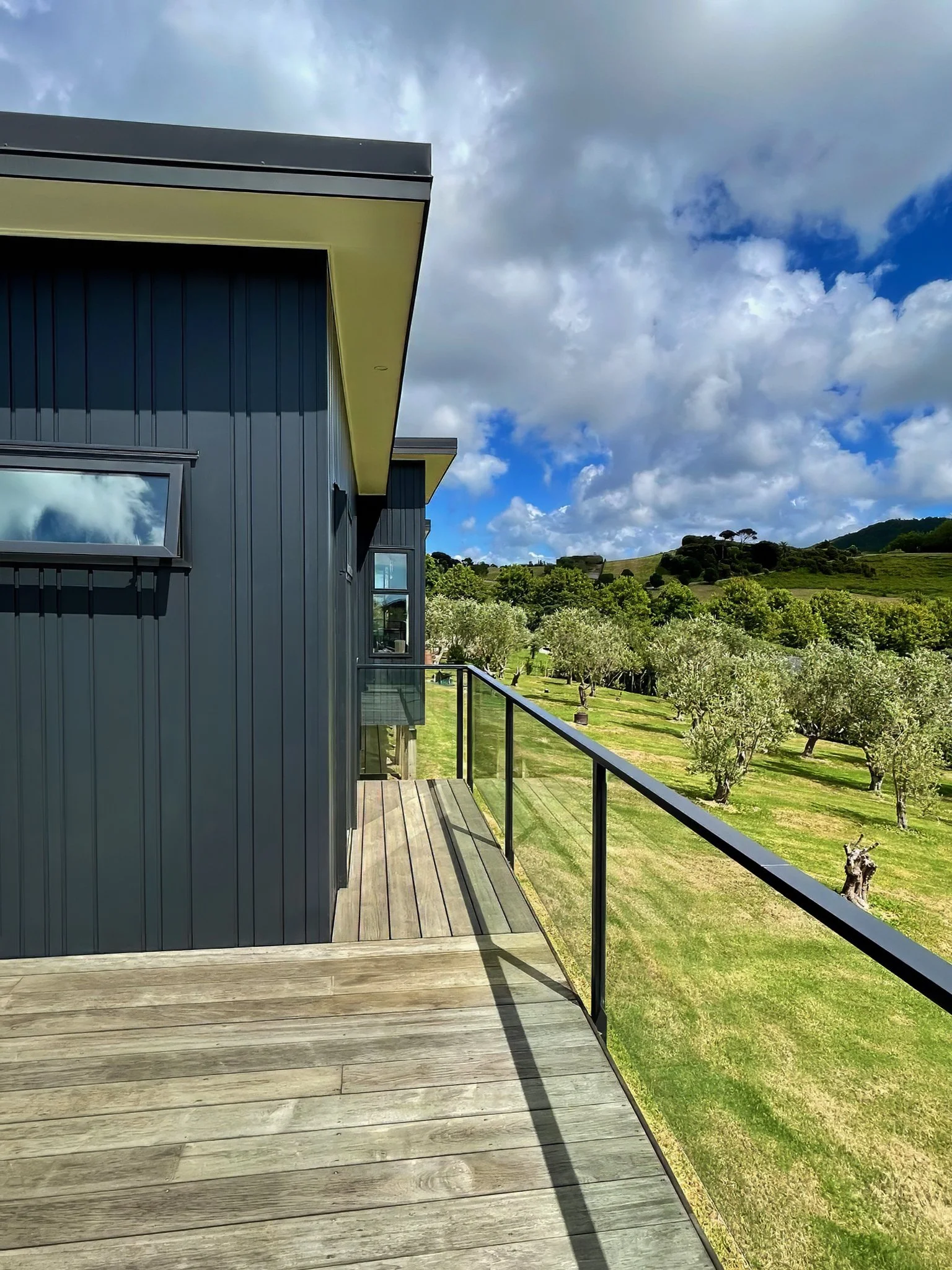 King Road new home side elevation with dark cladding and timber decking, Northland