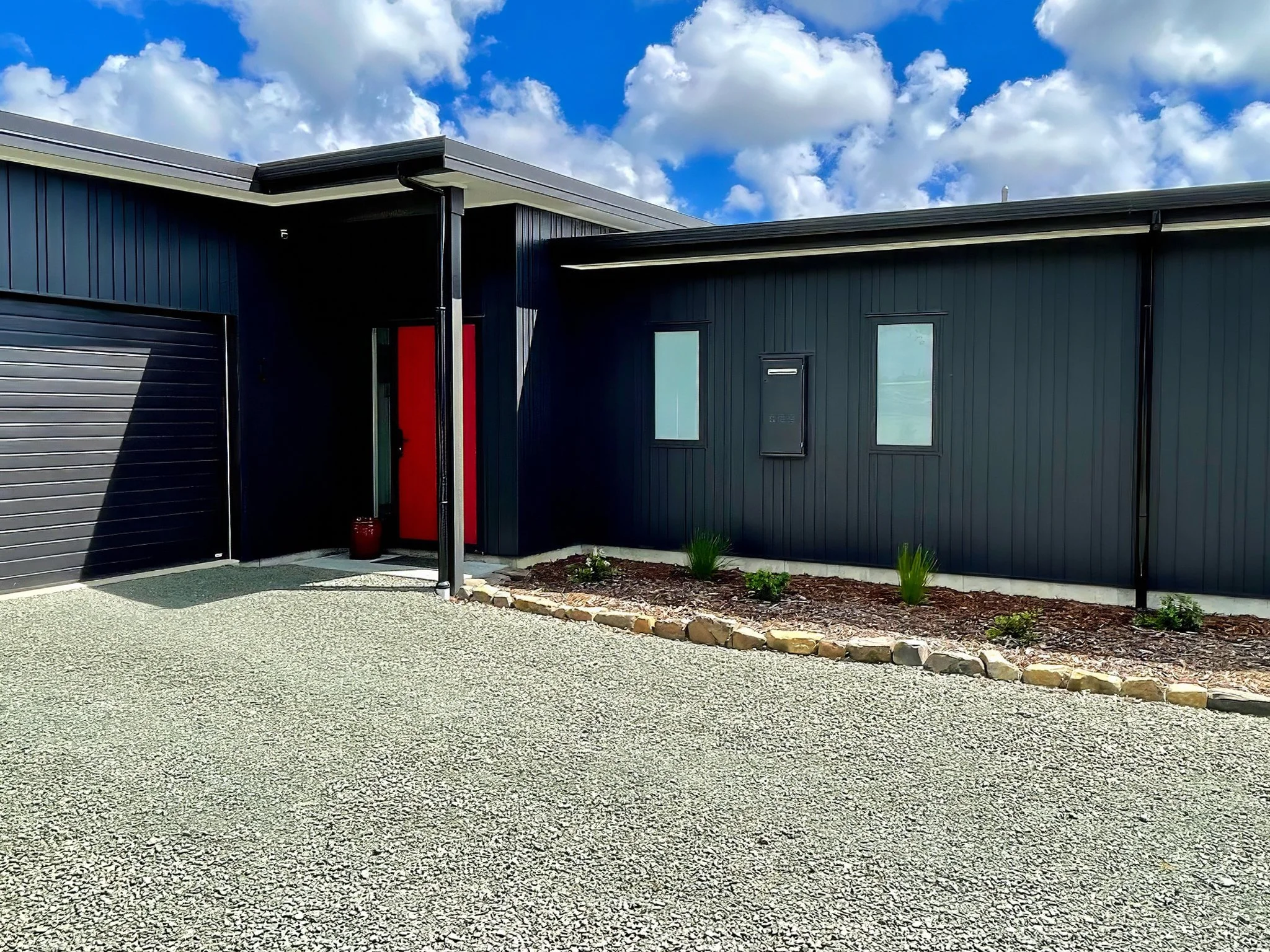 King Road luxury new home exterior with dark cladding and red door detail, Elite Building Mangawhai