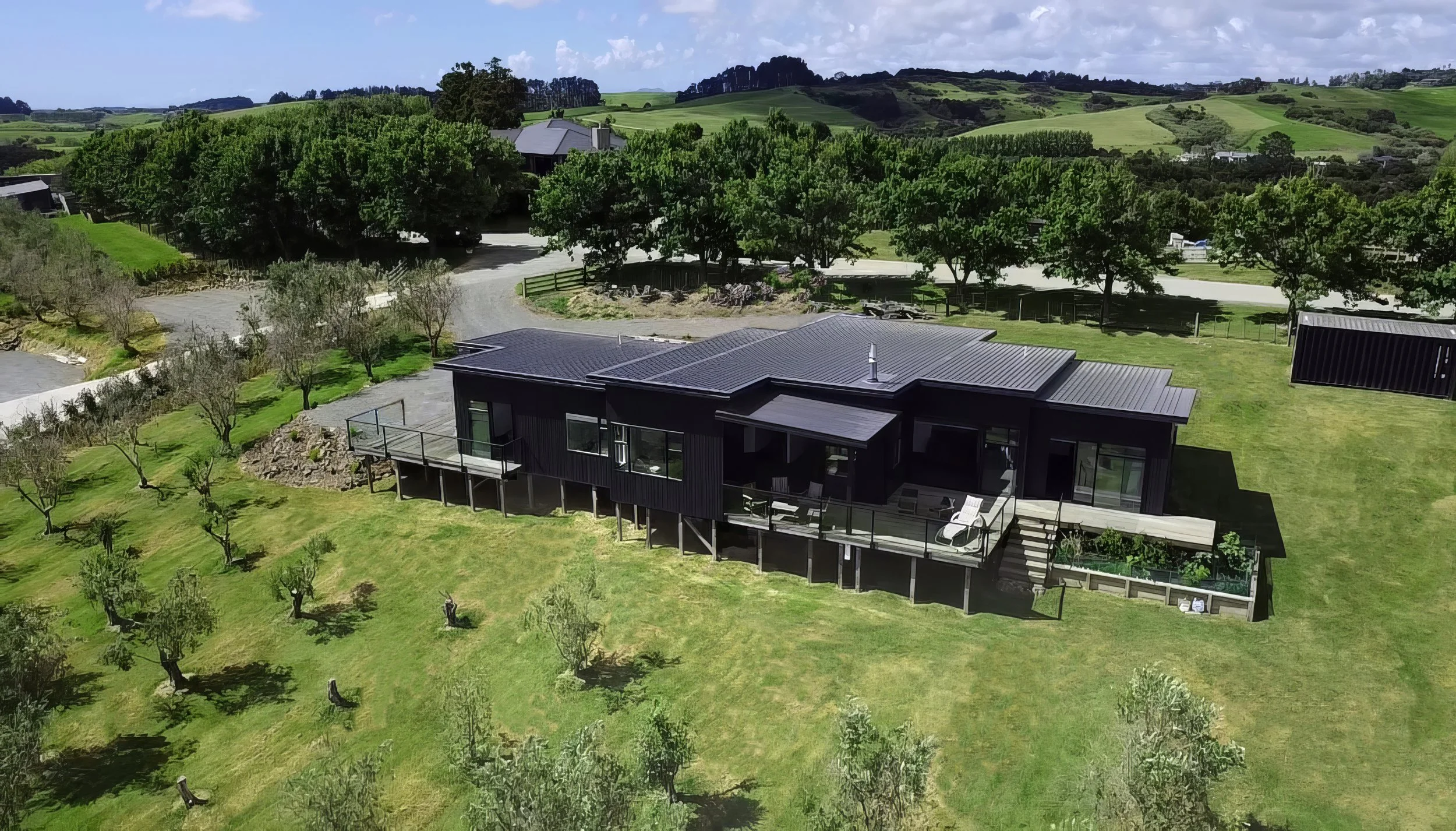 King Road new home with dark cladding and outdoor entertaining deck, aerial drone shot, Mangawhai