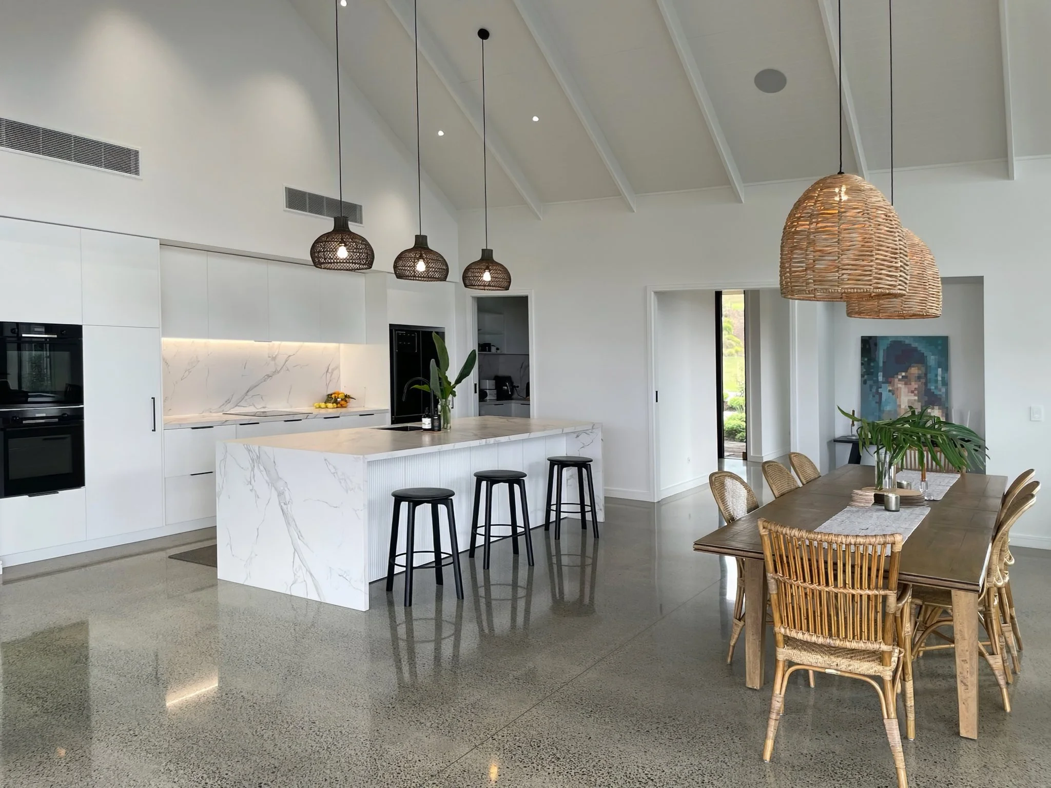 Sand Dune open plan kitchen and dining with rattan pendants and harbour views, Mangawhai