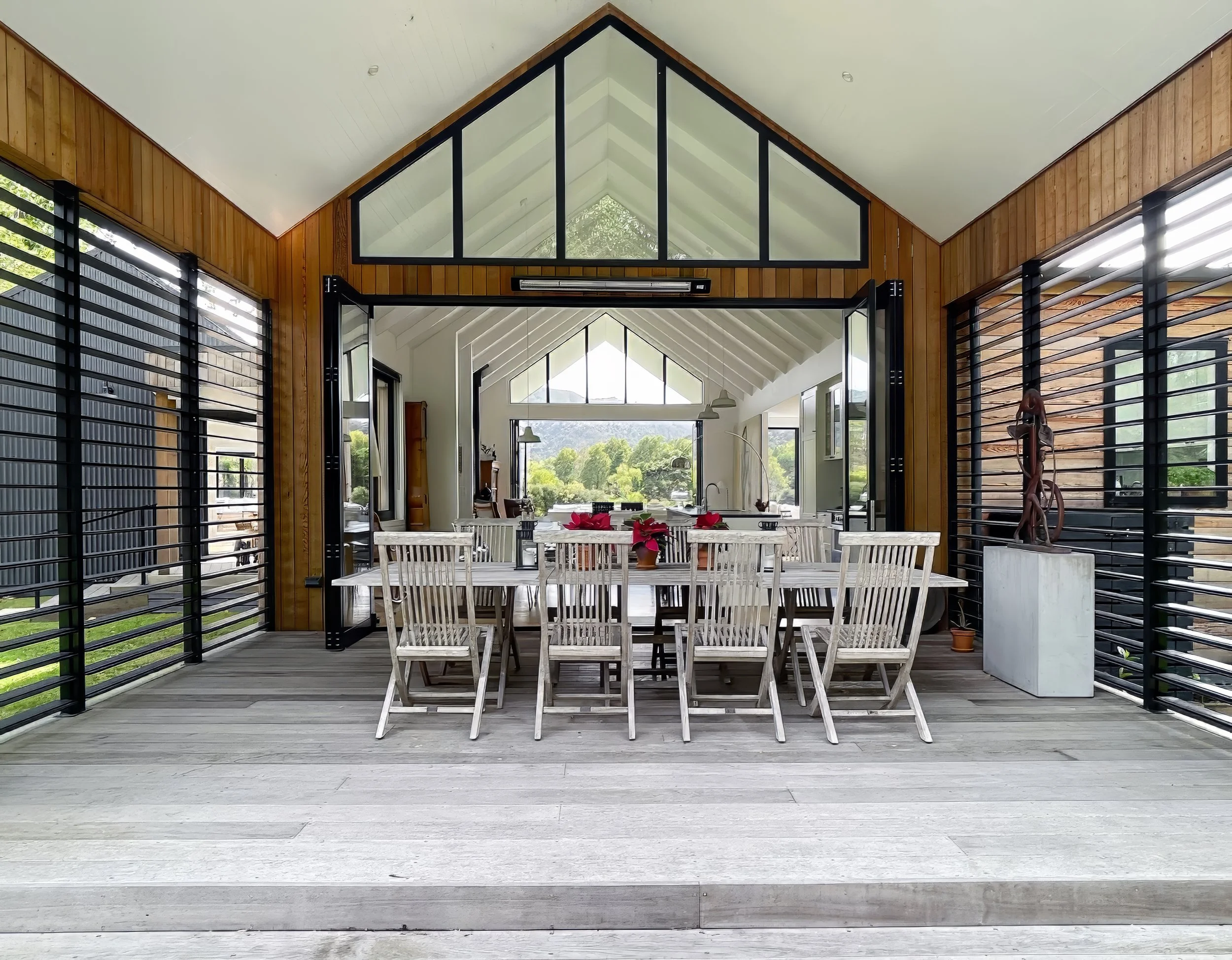Open plan outdoor dining table with vaulted ceiling and timber accents, Waiotahi Drive Elite Building Mangawhai