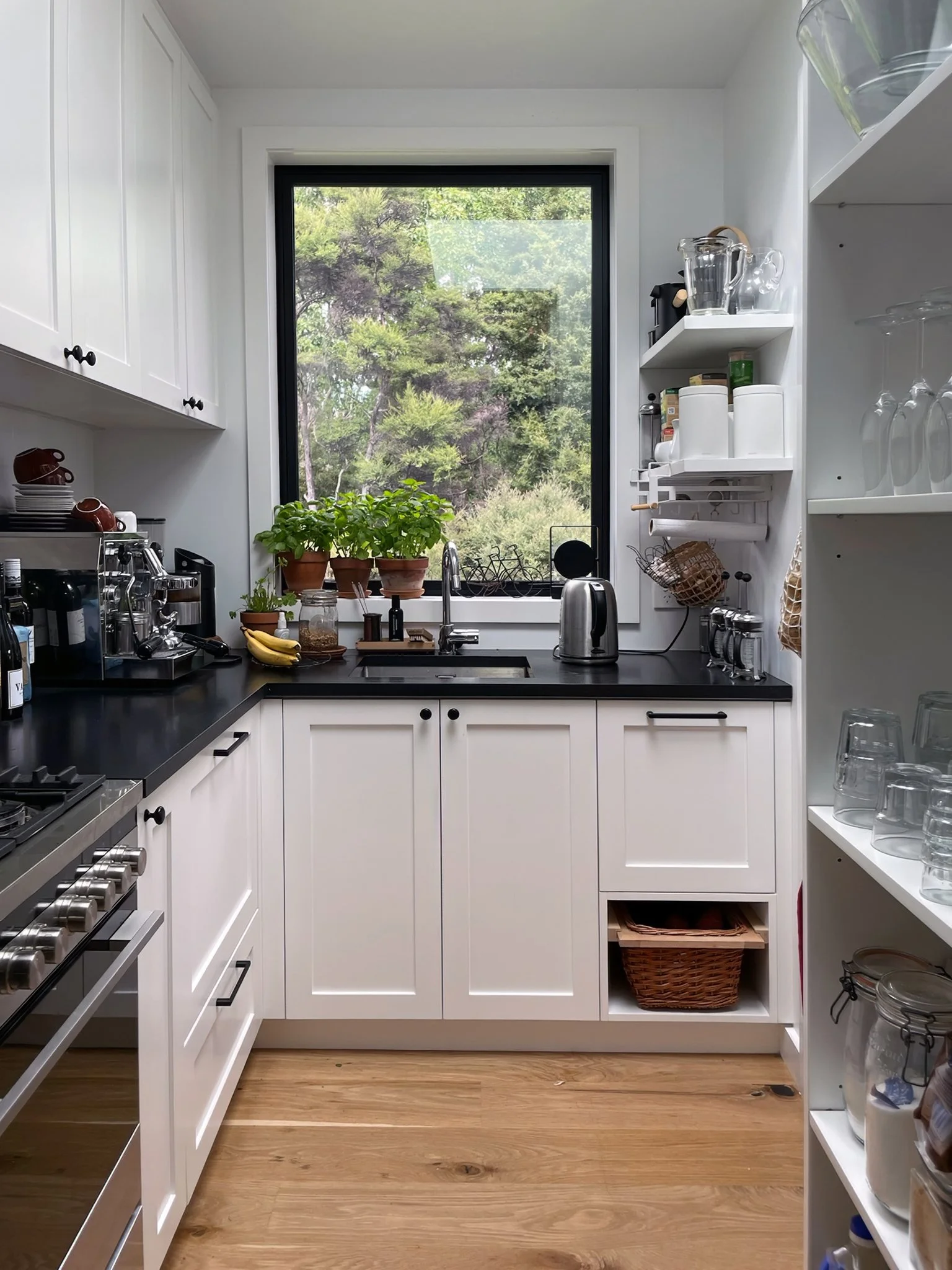 White kitchen with black benchtop and open shelving overlooking gardens, Waiotahi Drive Elite Building Mangawhai