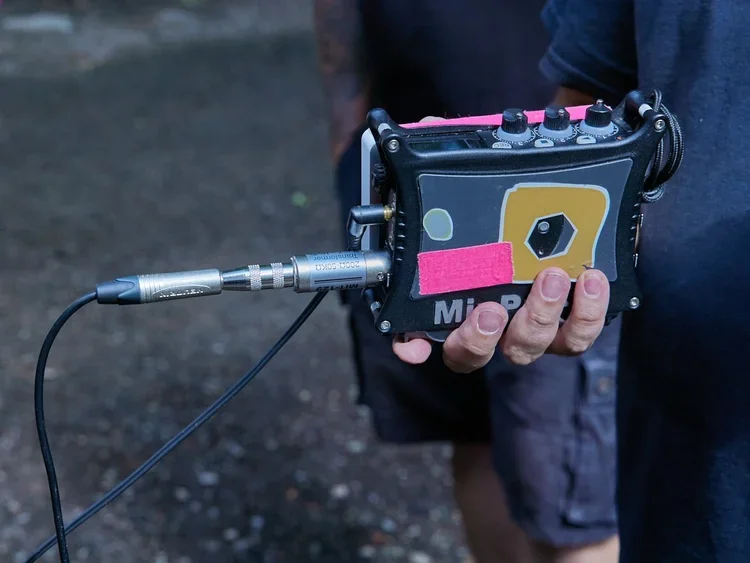 Person holding a handheld audio recorder with a microphone attached.